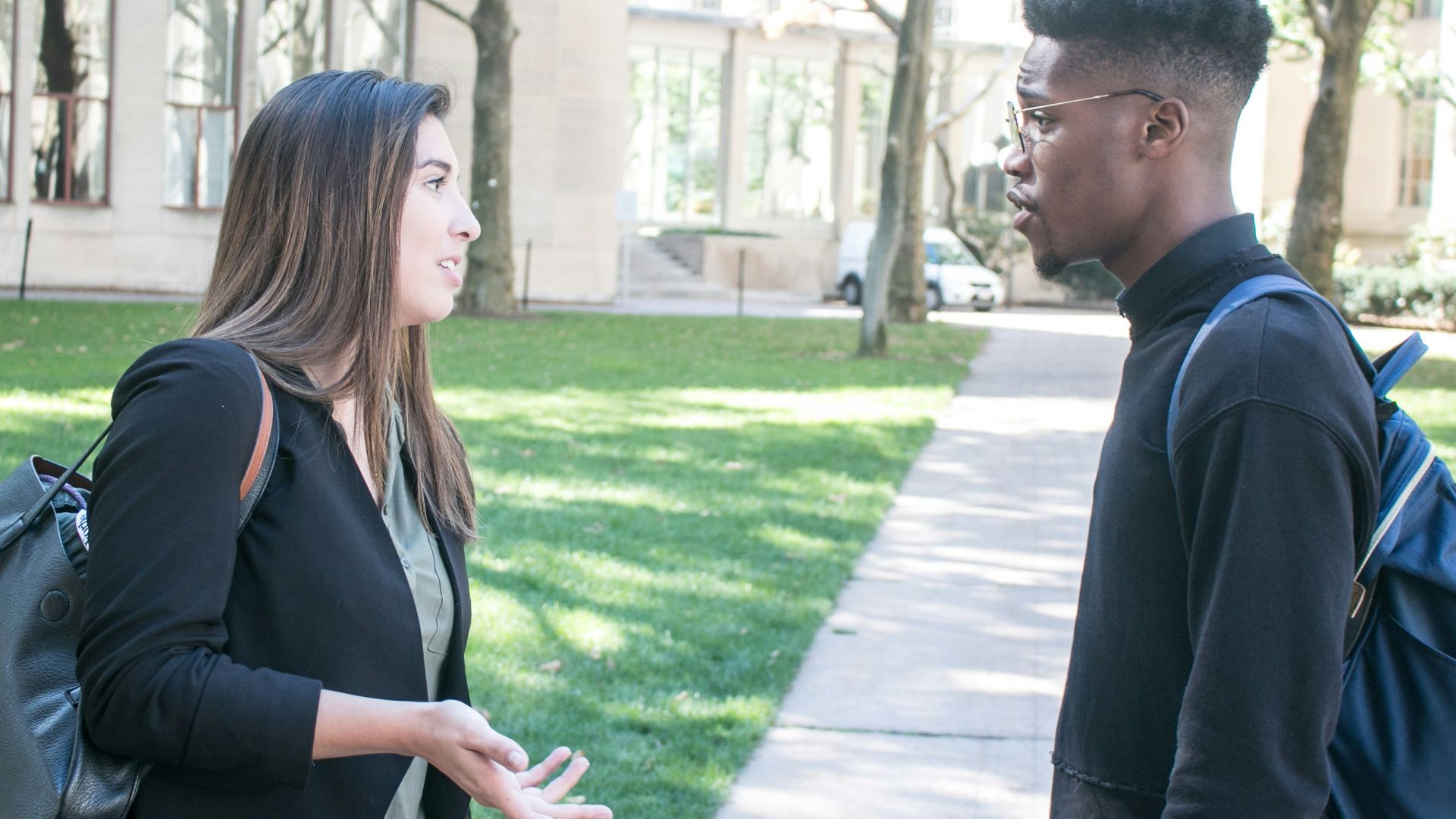 a man standing next to a woman on a sidewalk