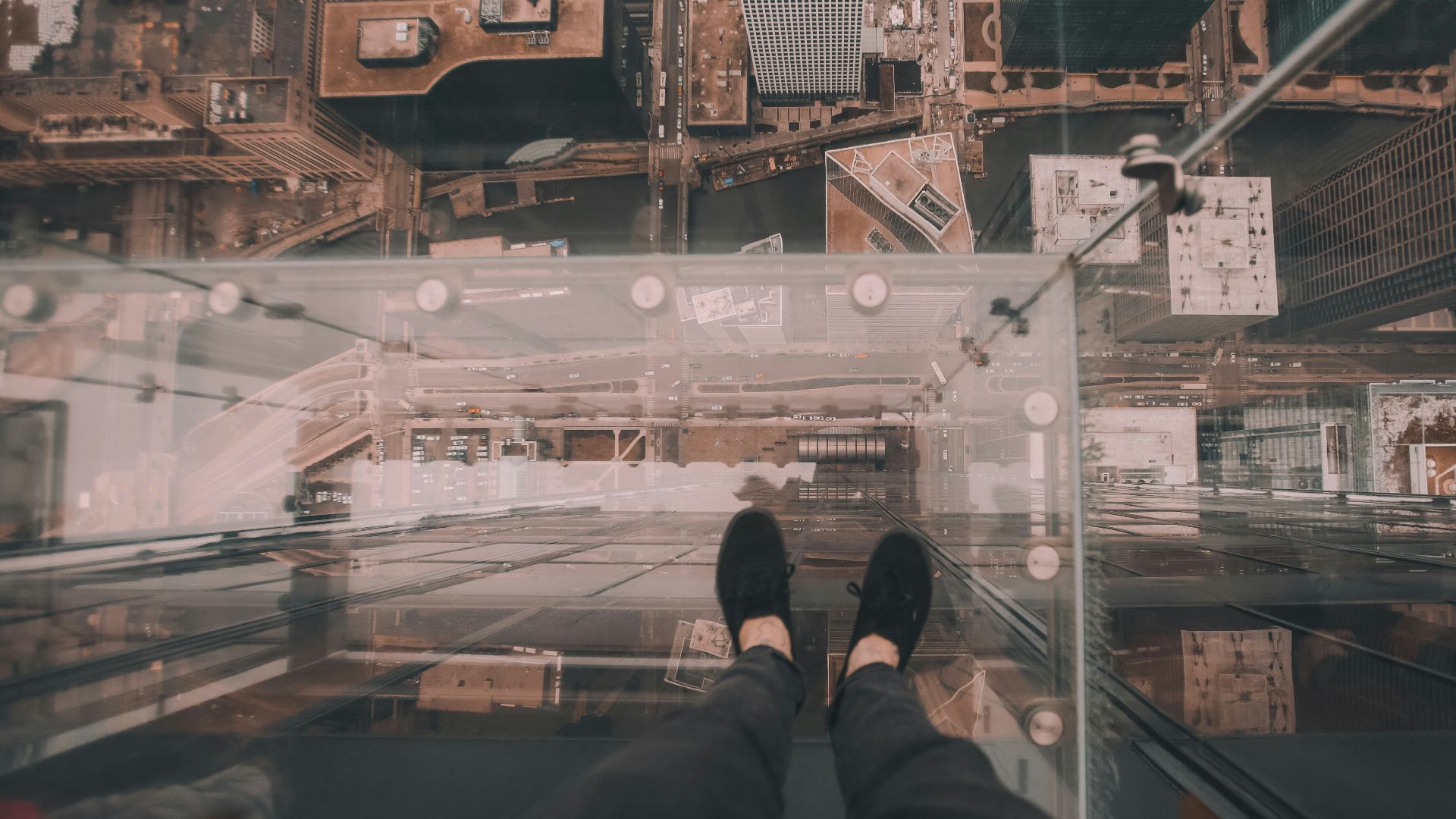 man standing on glass platform on top of building looking down on ground at daytime