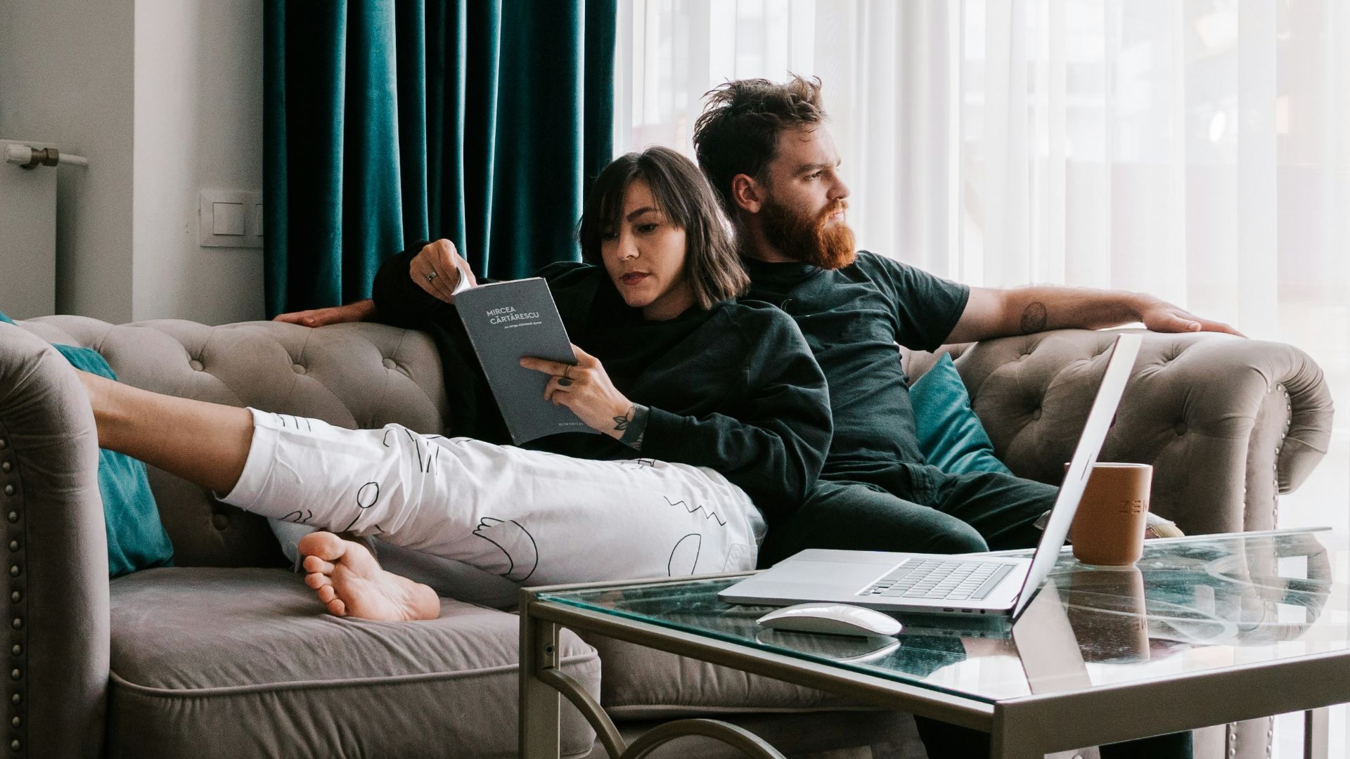 2 women sitting on sofa near window