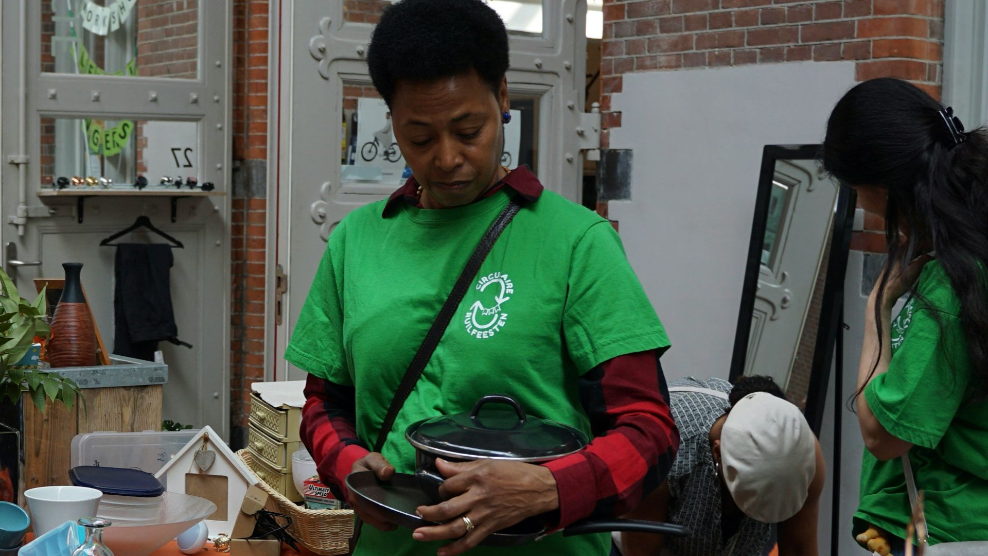 People shop at a yard sale, with items displayed.
