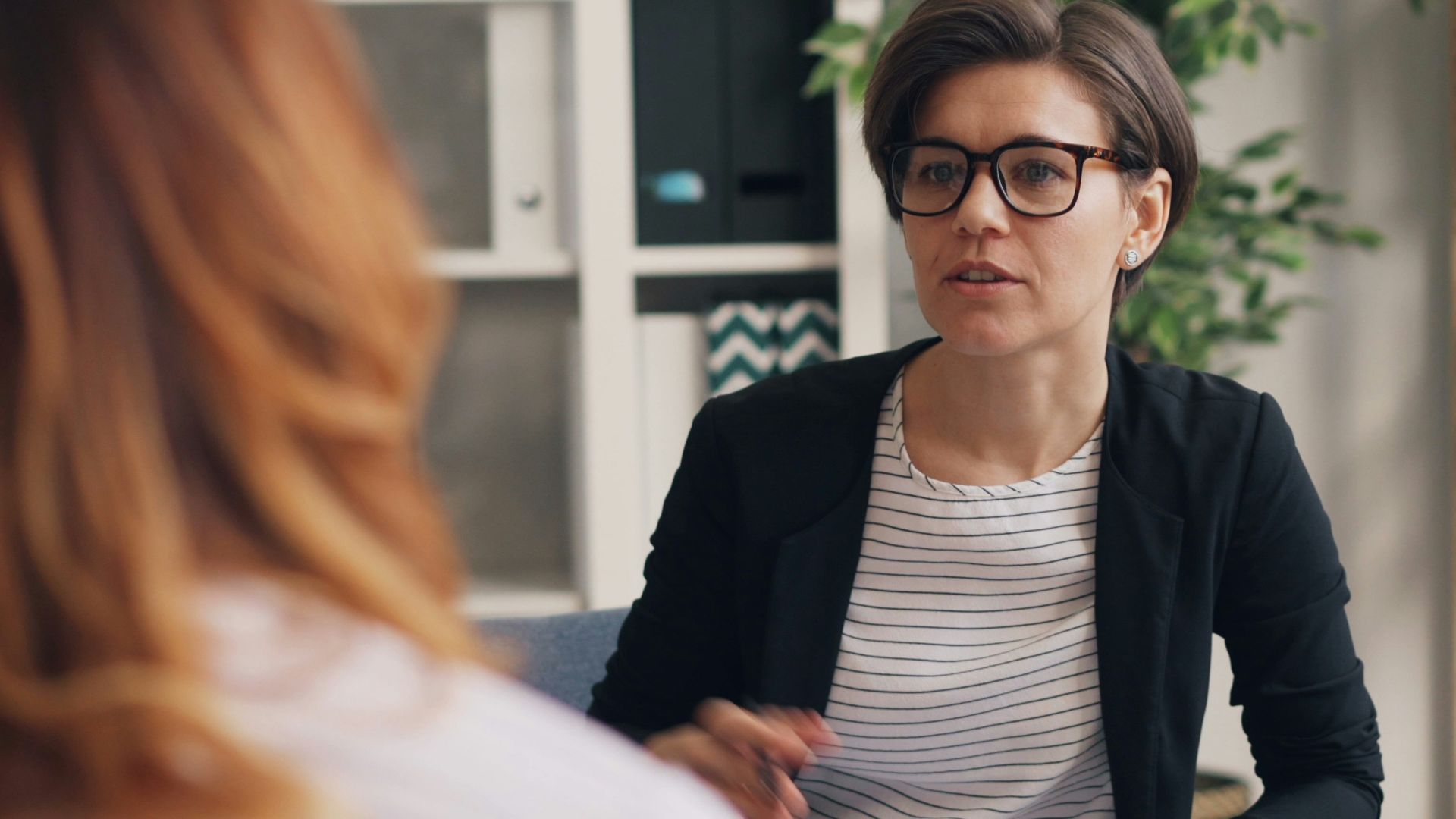 a woman sitting on a couch talking to another woman