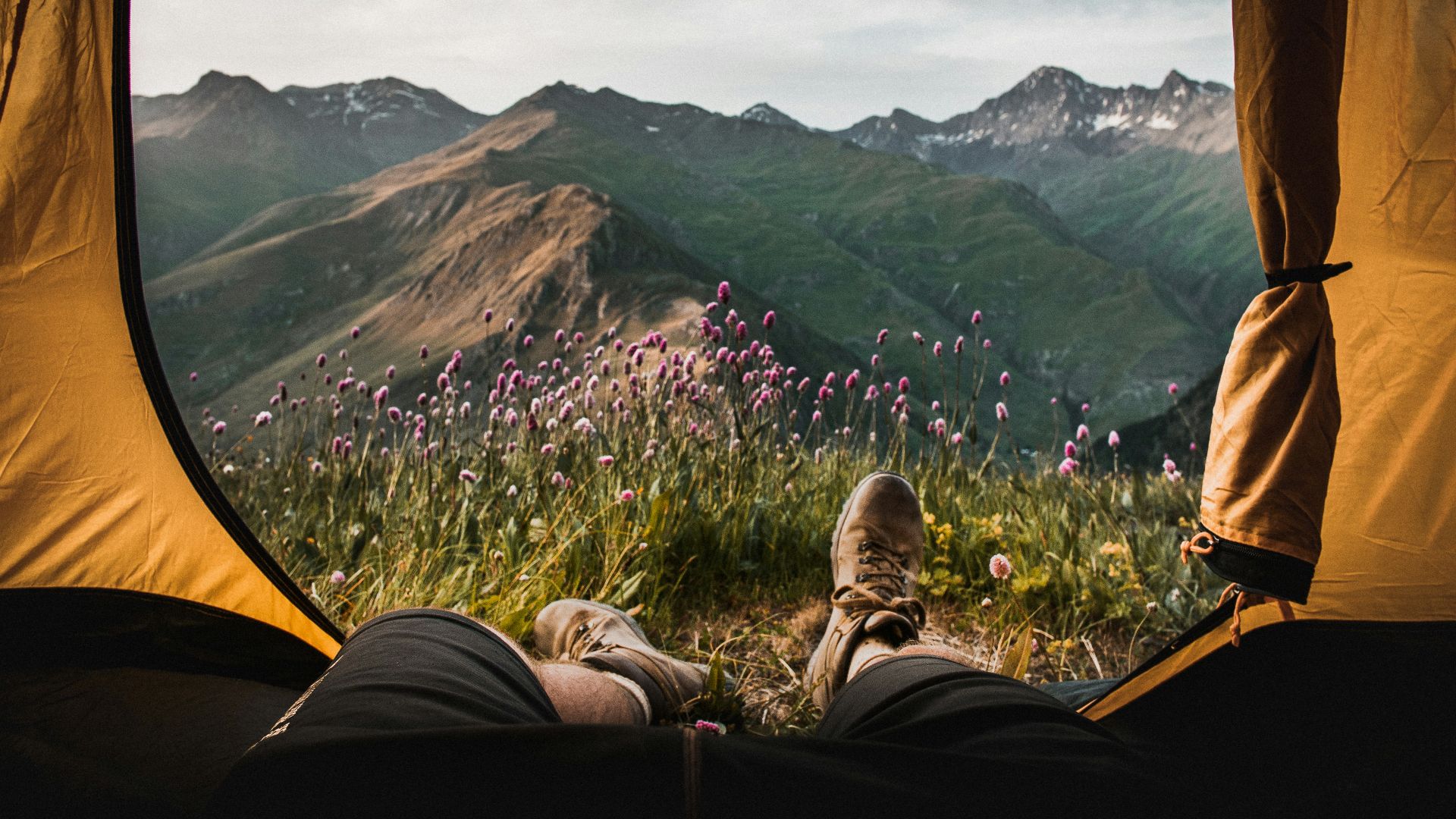 person lying inside tent and overlooking mountain
