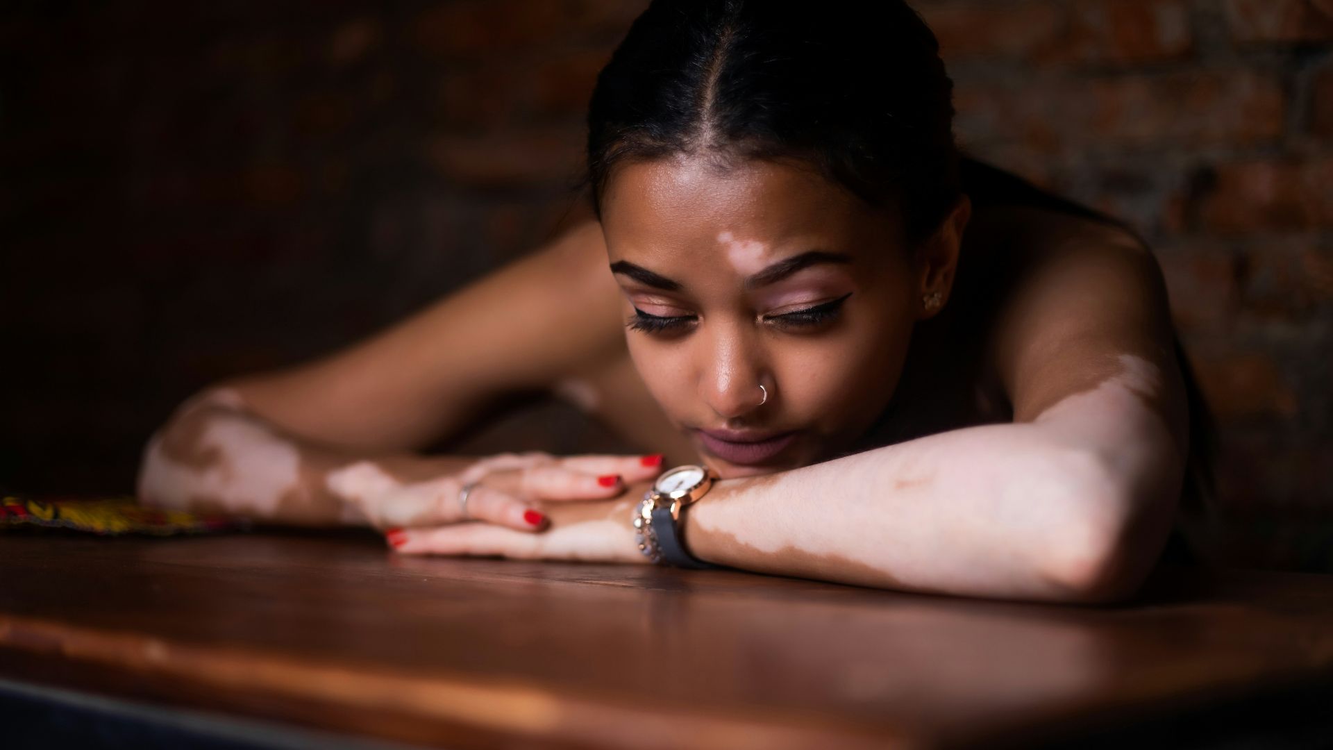 woman in red and white floral dress lying on brown wooden table