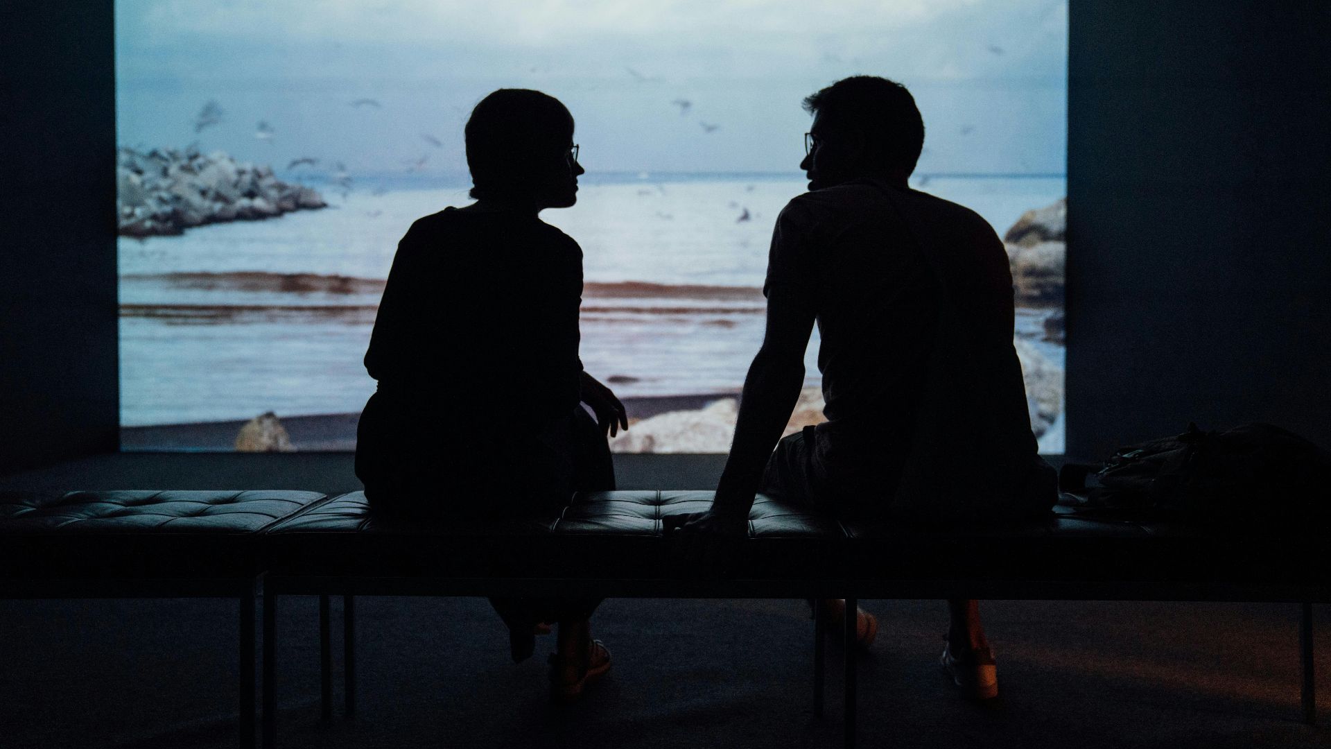 silhouette of man and woman sitting on ottoman
