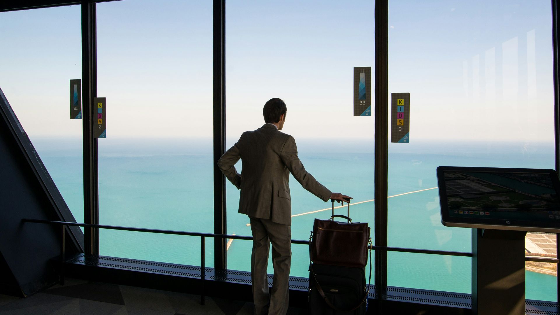 man in white shirt standing near glass window