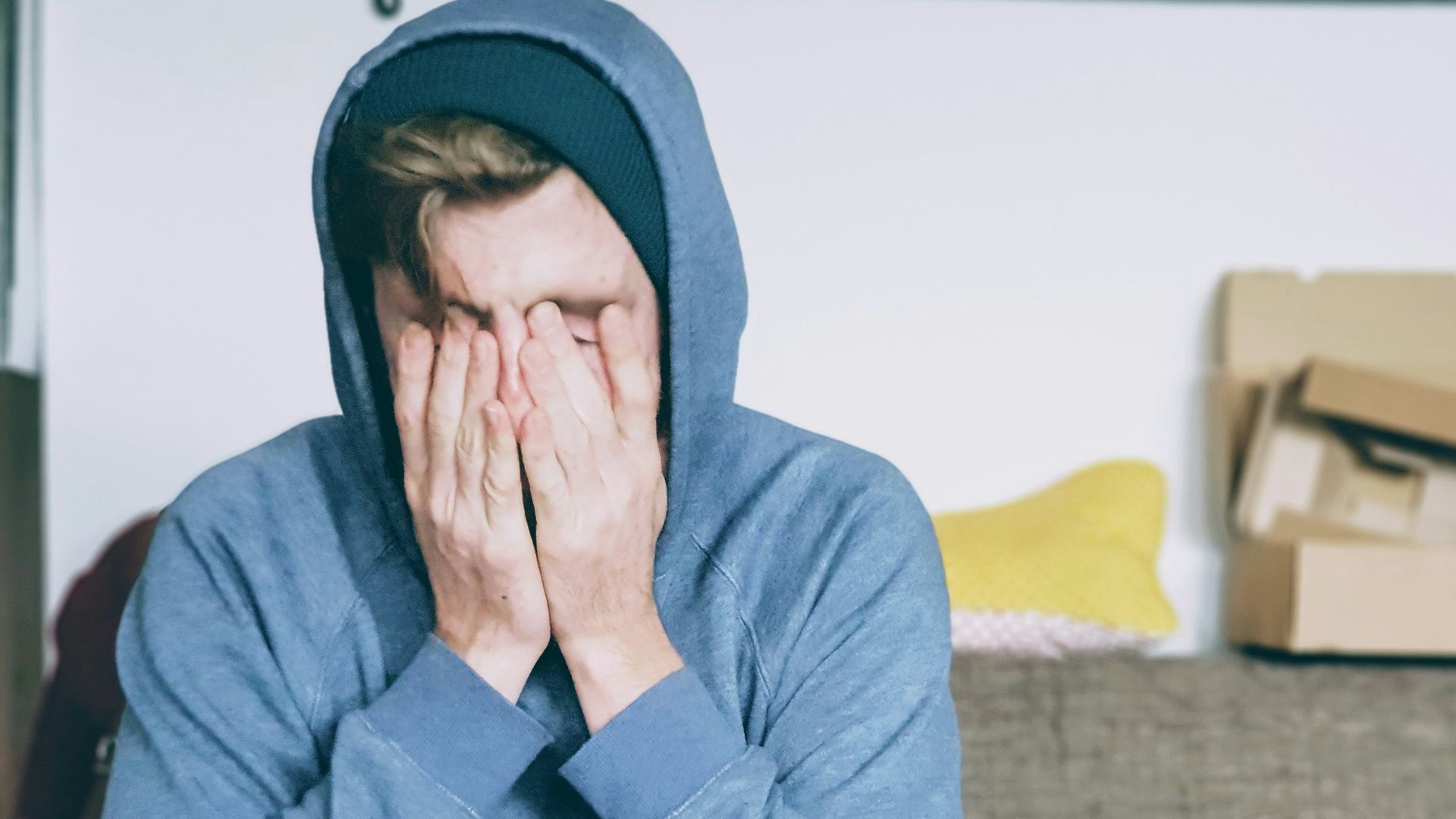 man covering face with both hands while sitting on bench