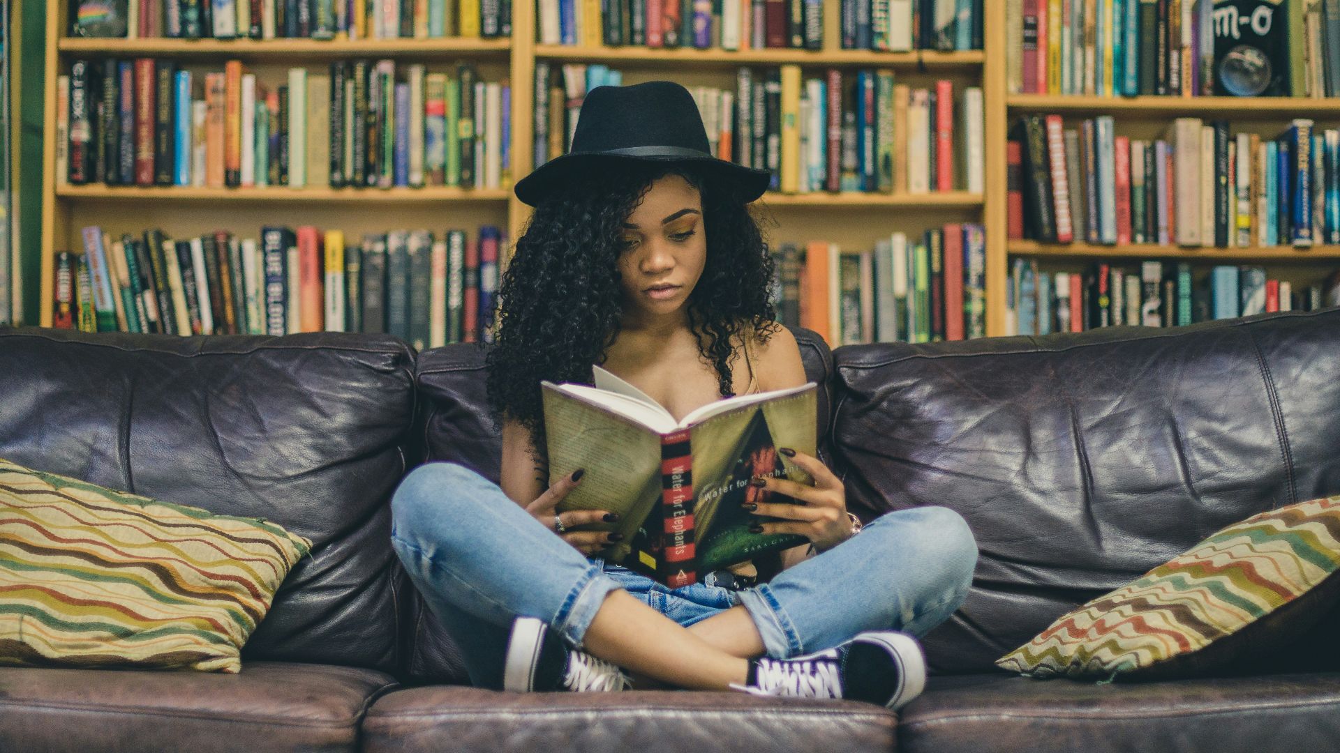 woman reading a book while sitting on black leather 3-seat couch