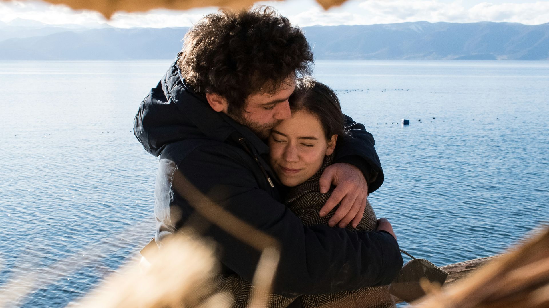 man and woman hugging each other near body of water during daytime