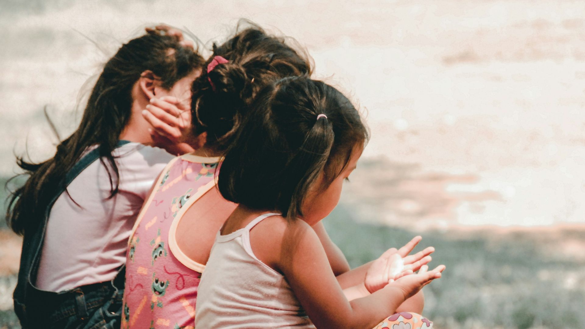 three children sitting on grass
