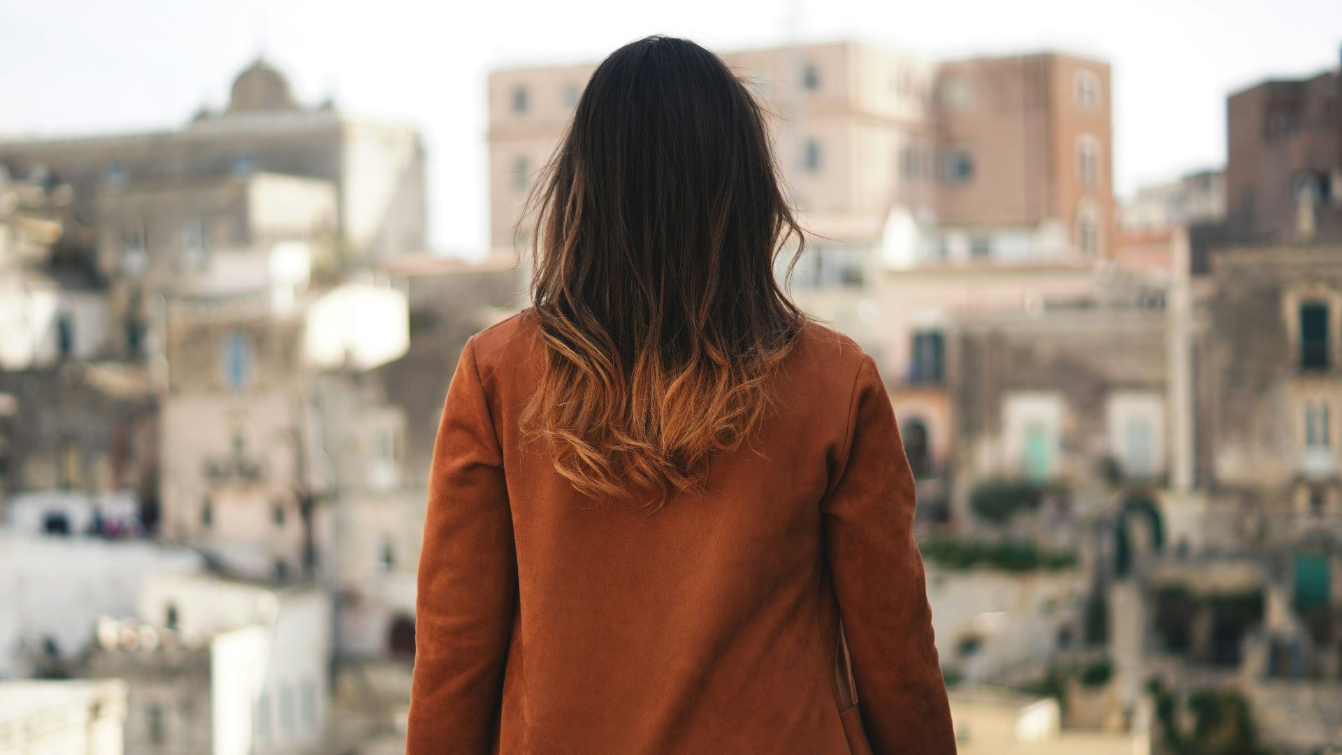 woman in brown long sleeve shirt sitting on gray rock during daytime