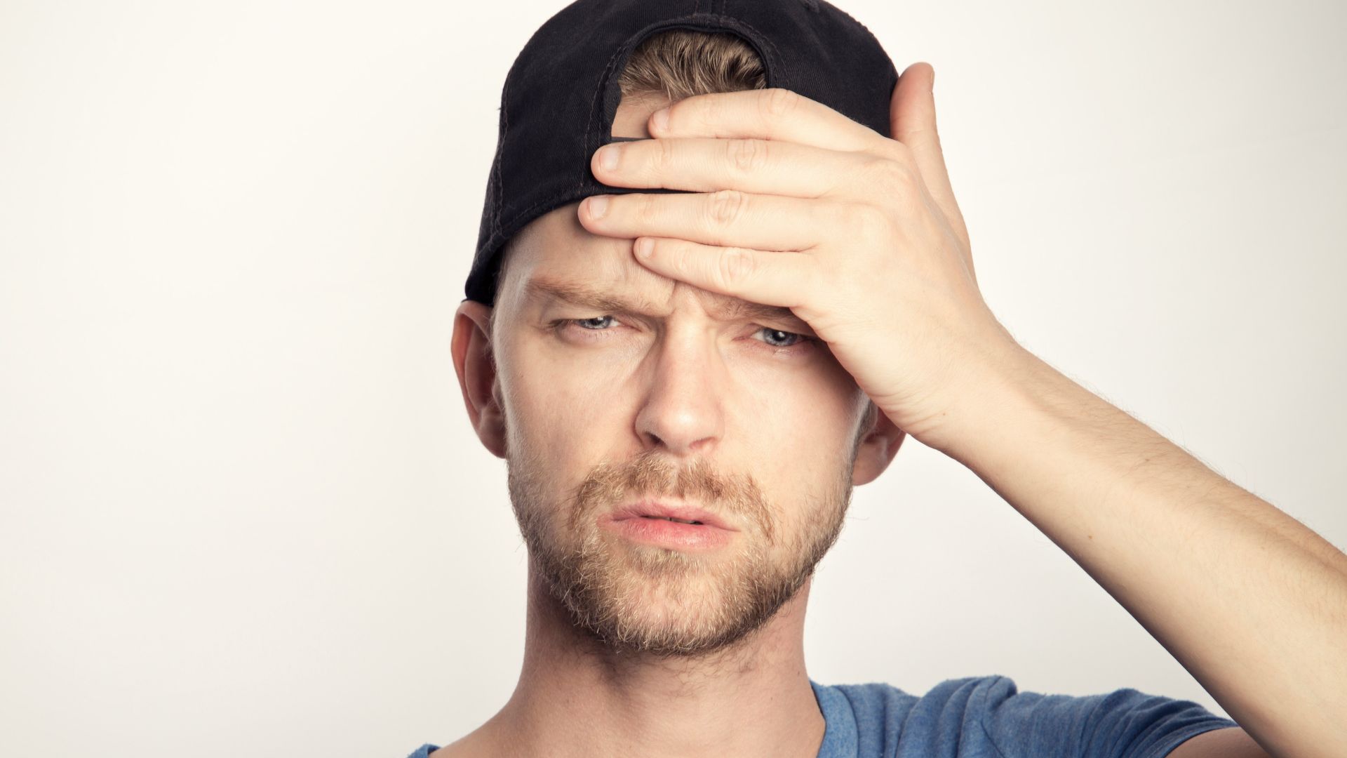 man in blue crew neck shirt covering his face