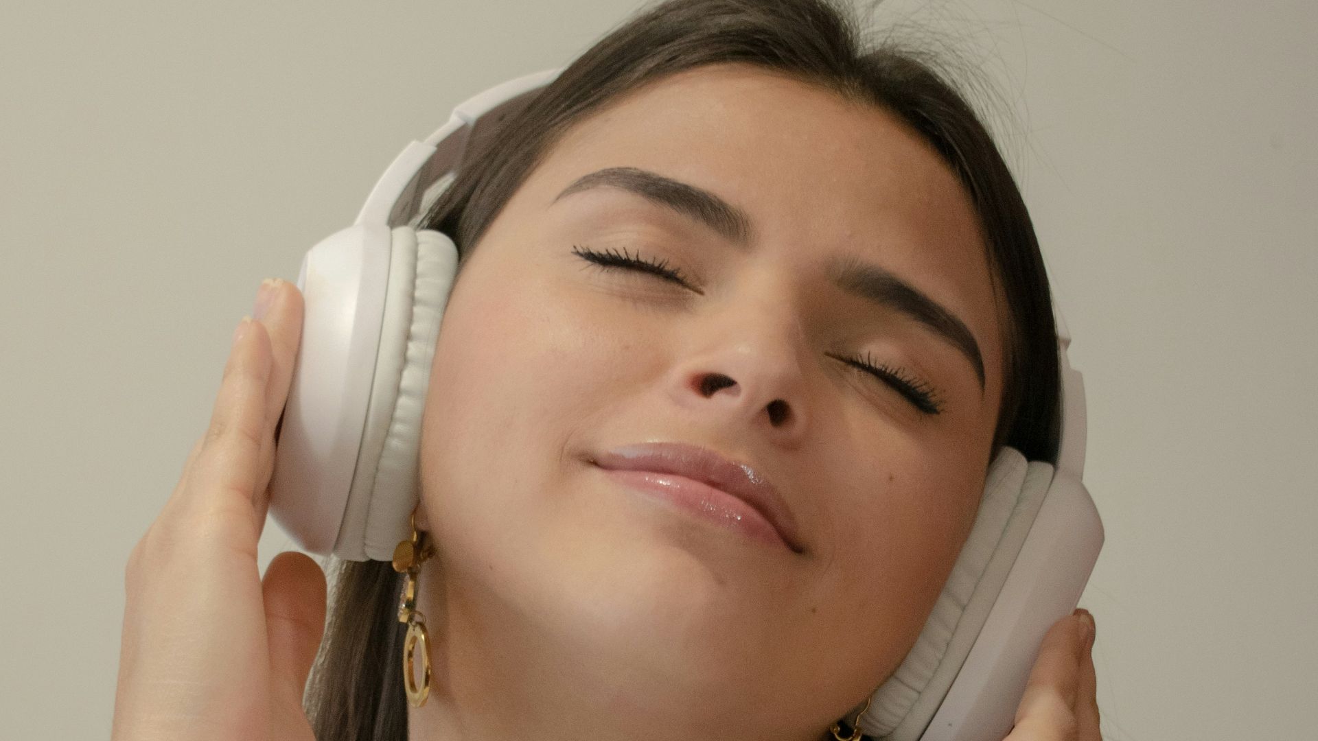 a woman with her eyes closed holding a phone to her ear