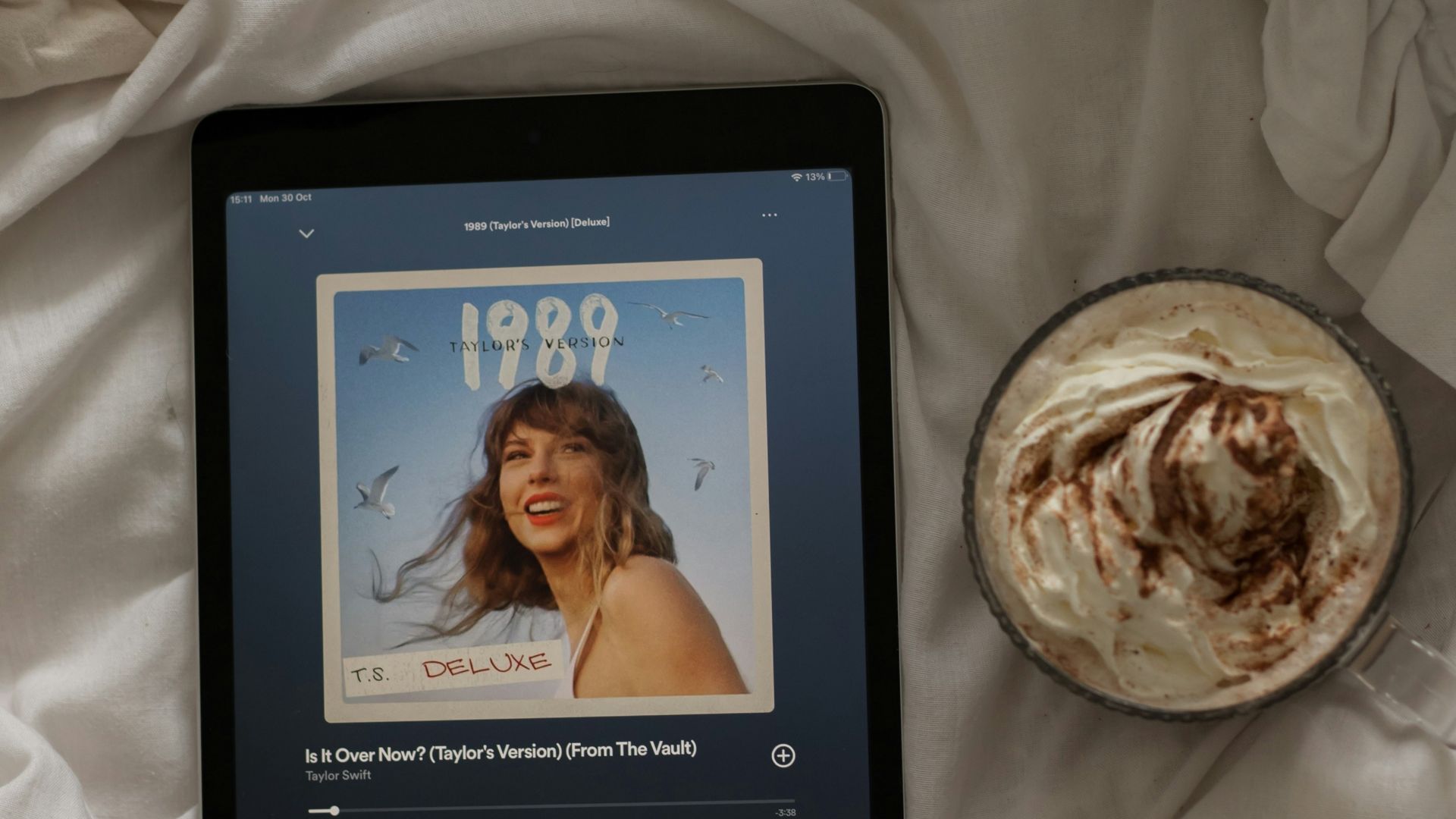 a tablet sitting on top of a bed next to a cup of coffee