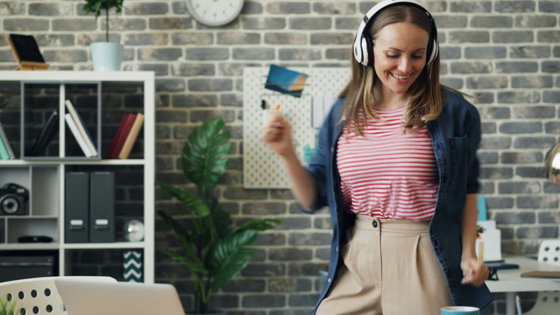 a woman wearing headphones standing in front of a laptop
