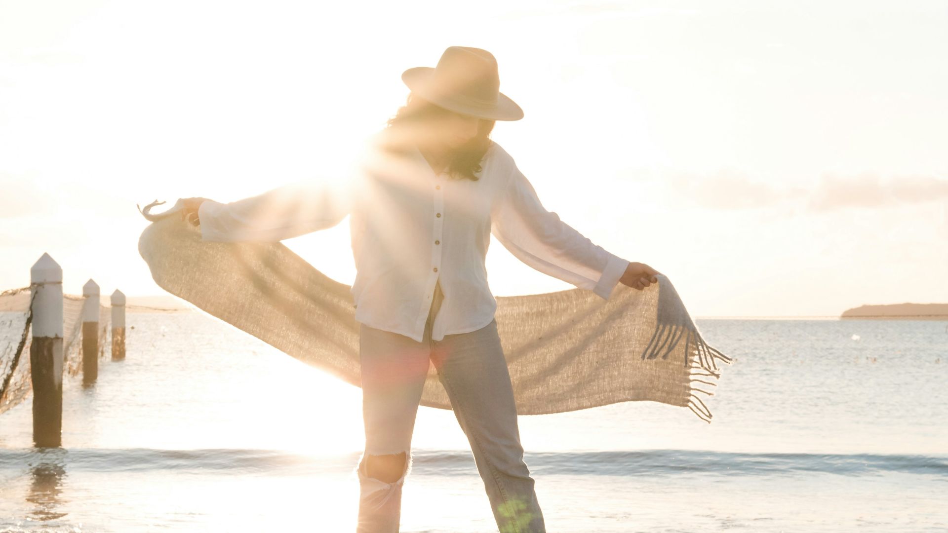 man standing on shore holding white textile front of sea