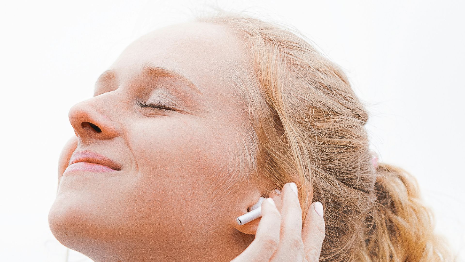 woman in white crew neck shirt covering her face with her hand