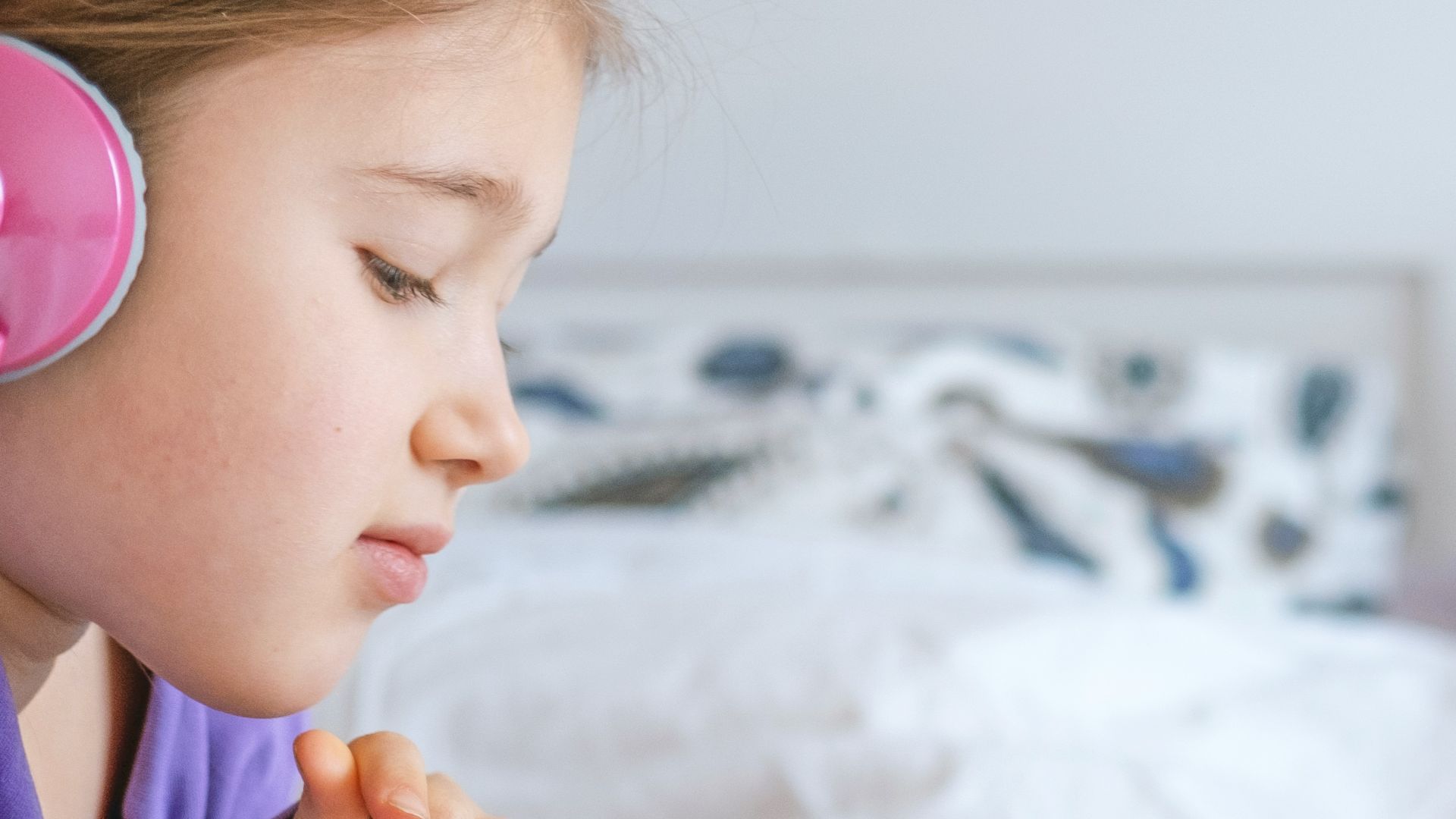 a little girl laying in bed with headphones on