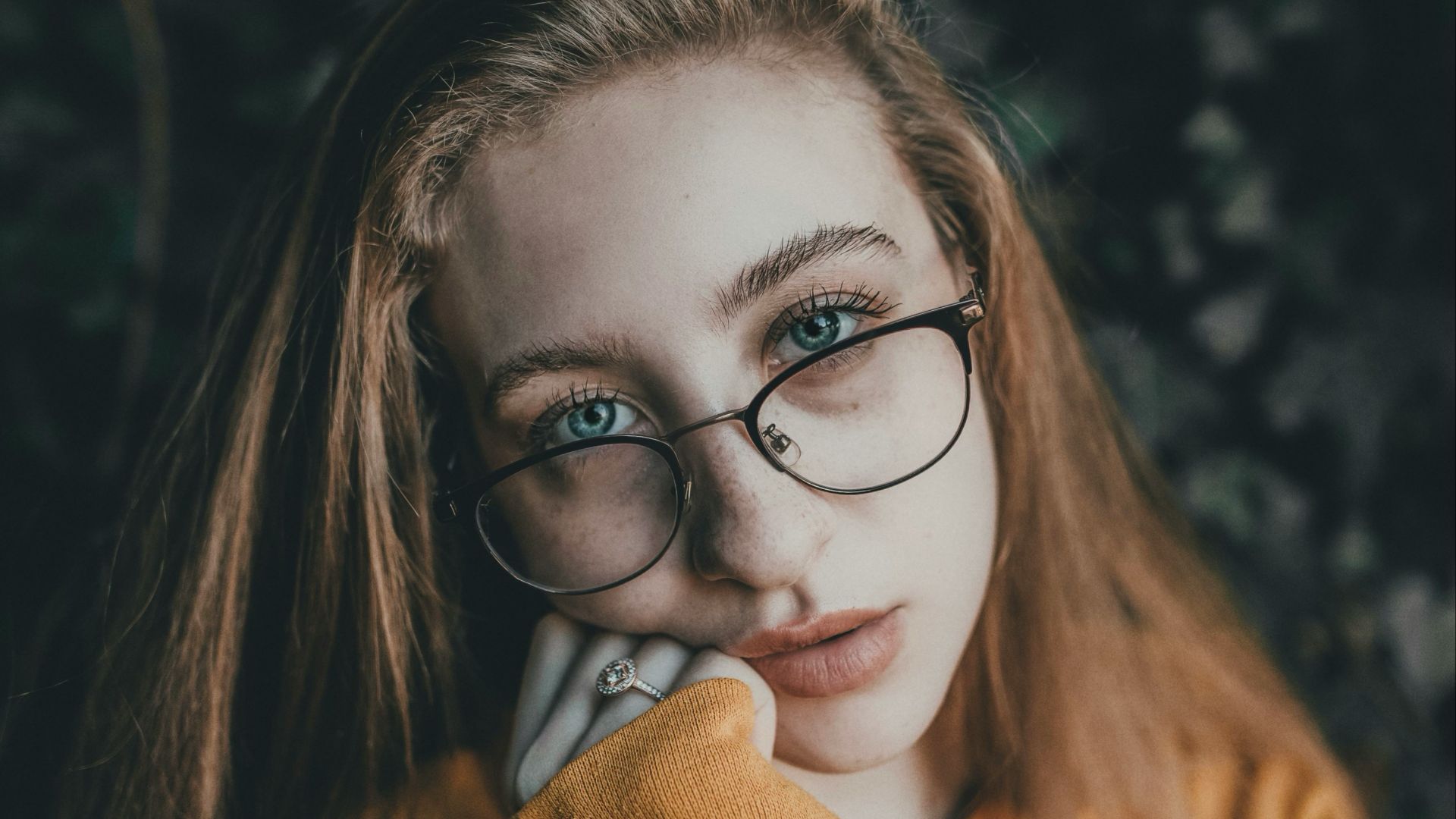 woman in brown hoodie wearing black framed eyeglasses