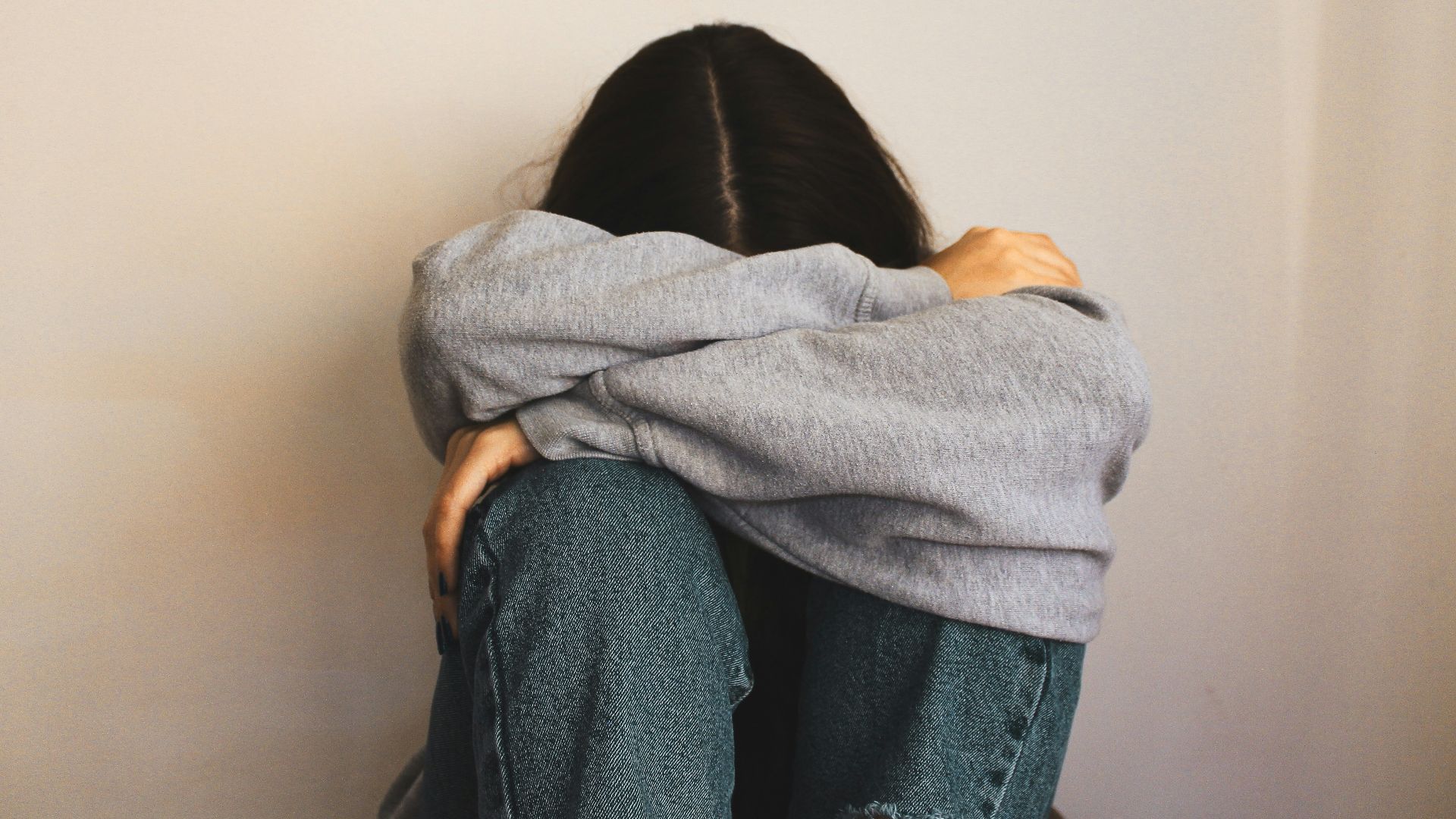 a woman sitting on the floor with her arms wrapped around her head