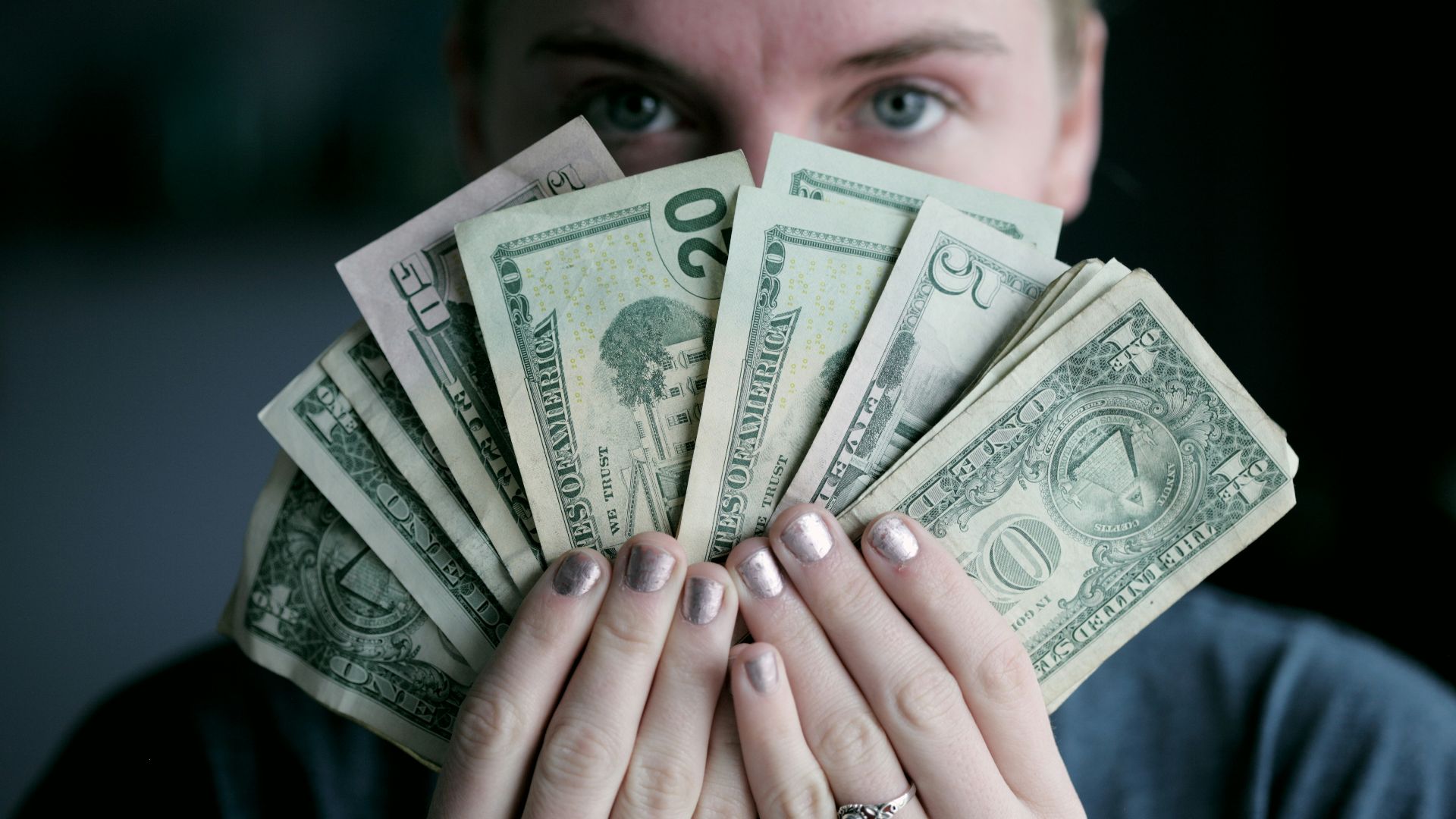 person holding fan of U.S. dollars banknote