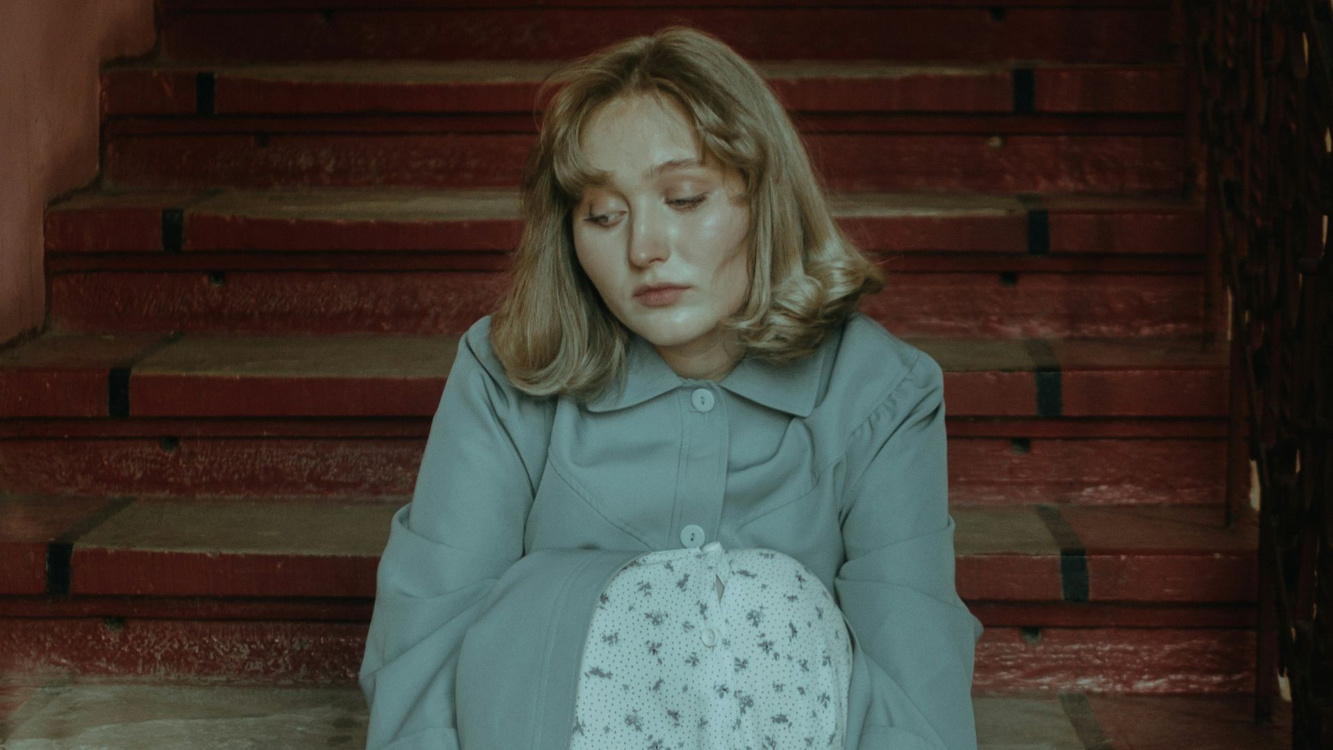 girl in pink long sleeve shirt and white skirt sitting on brown wooden staircase