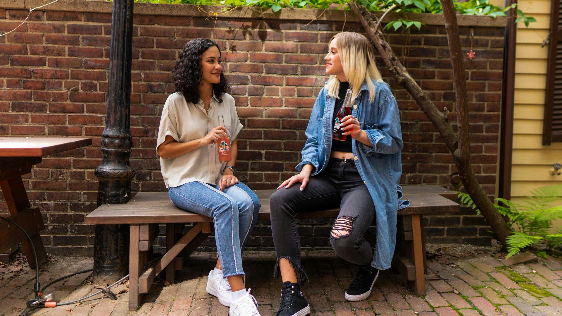 2 women sitting on brown wooden bench