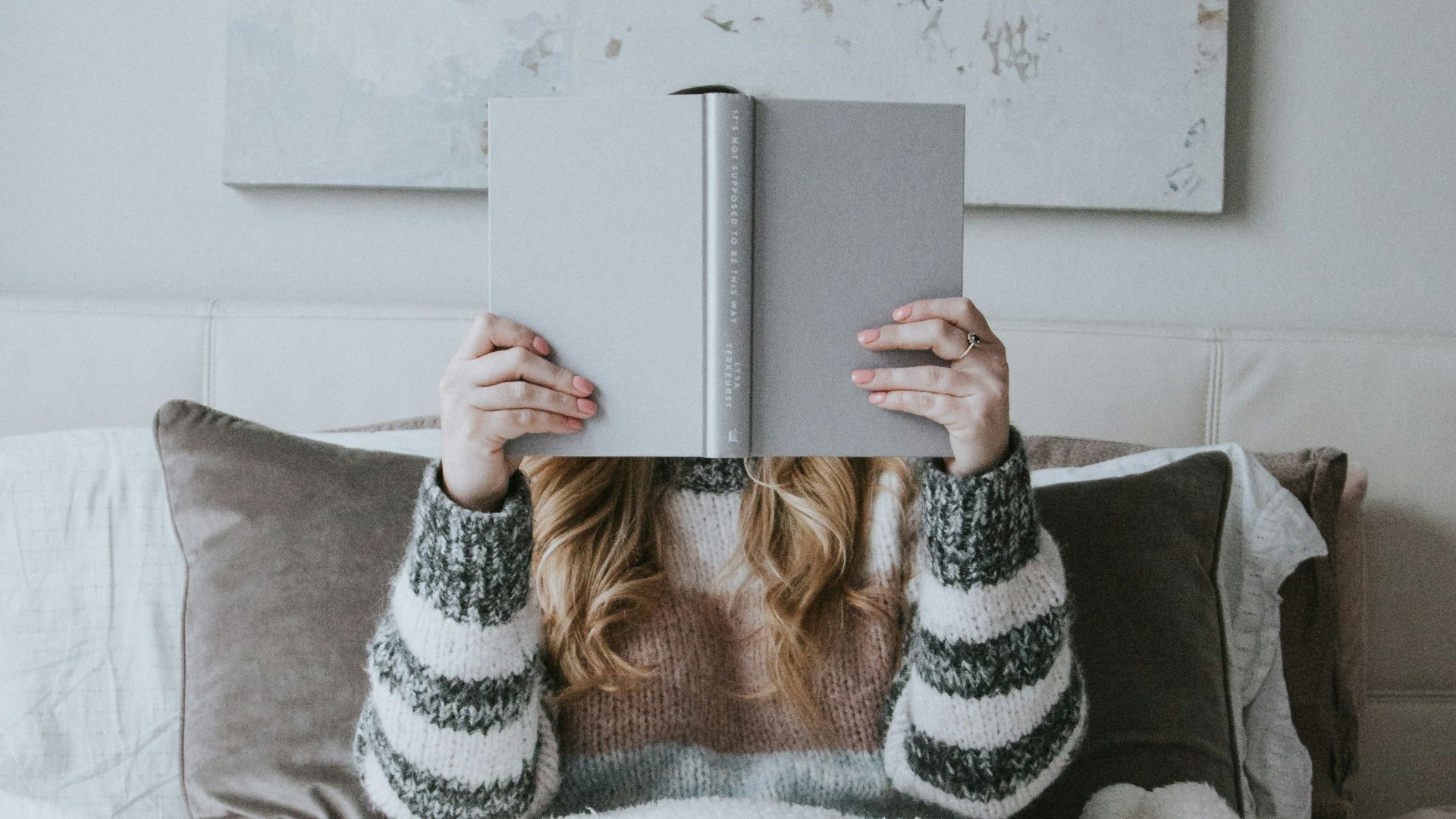 woman sitting on bed while holding book
