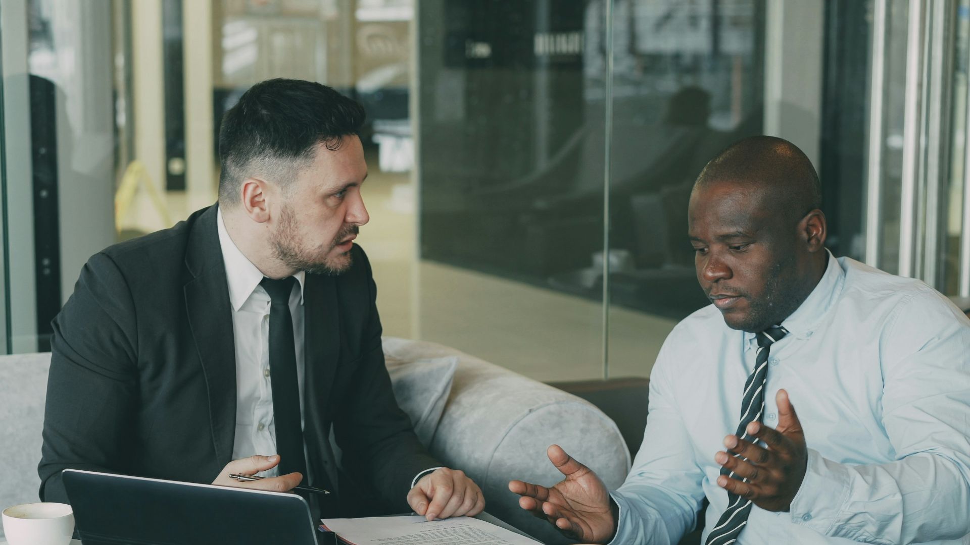Two businessmen discussing documents at a table.