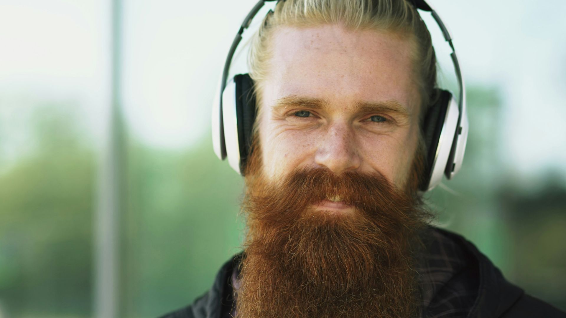 Man with beard wearing headphones outdoors
