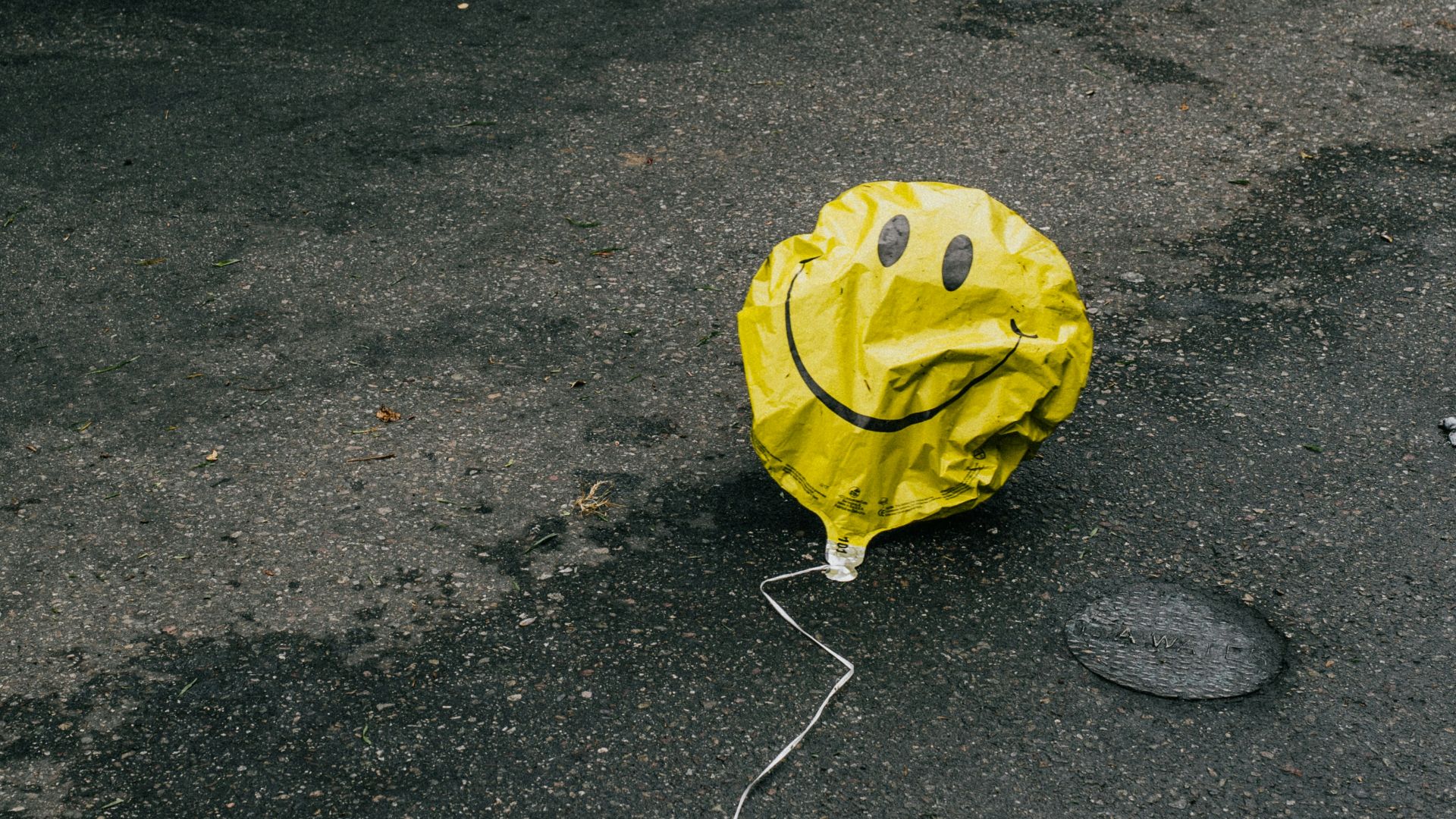 smiling emoji balloon beside black car during daytime