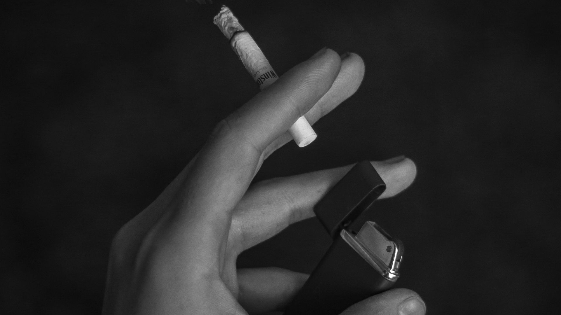 grayscale photo of person holding cigarette stick