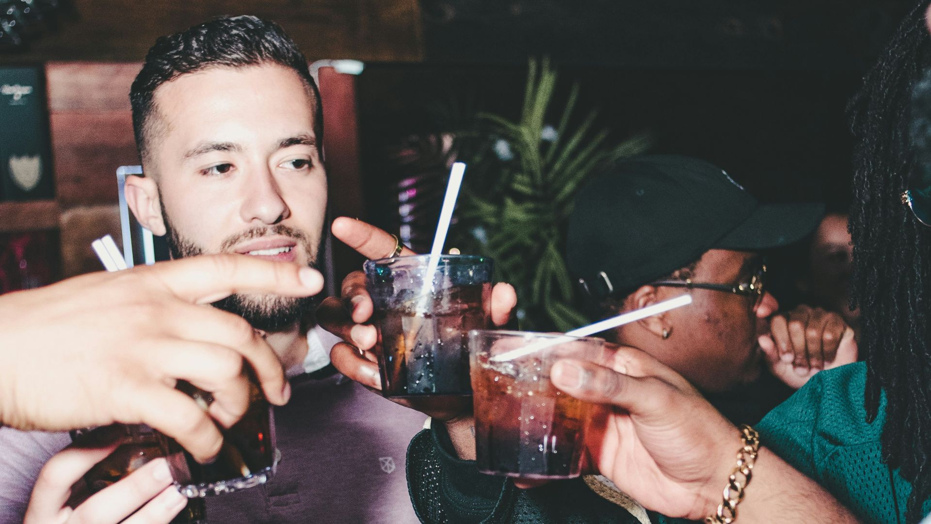 three people holding glass bottles while talking