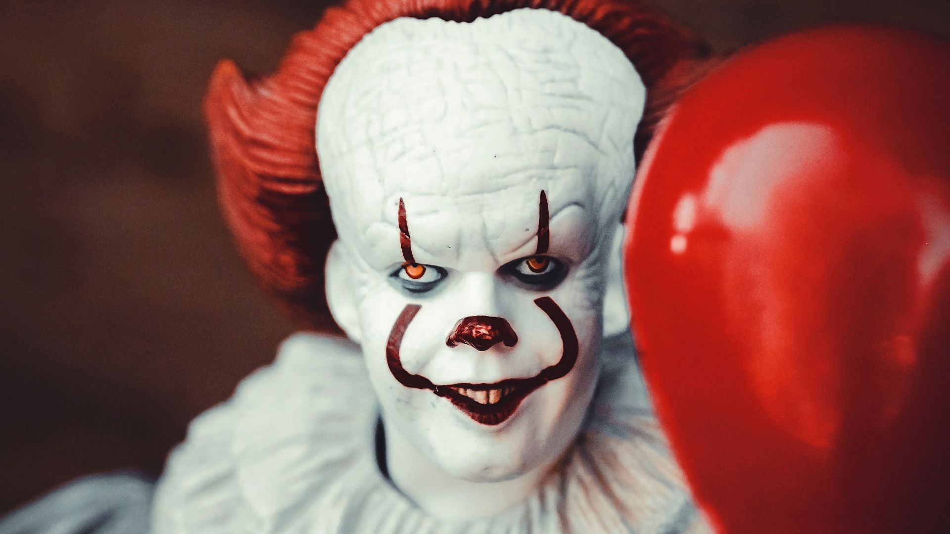 white and red clown holding heart balloon