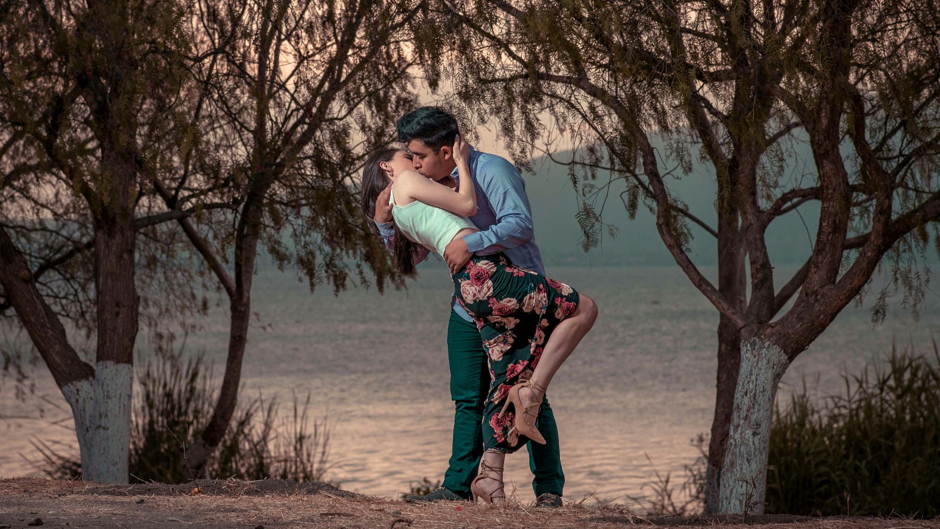 couple kissing in front of trees