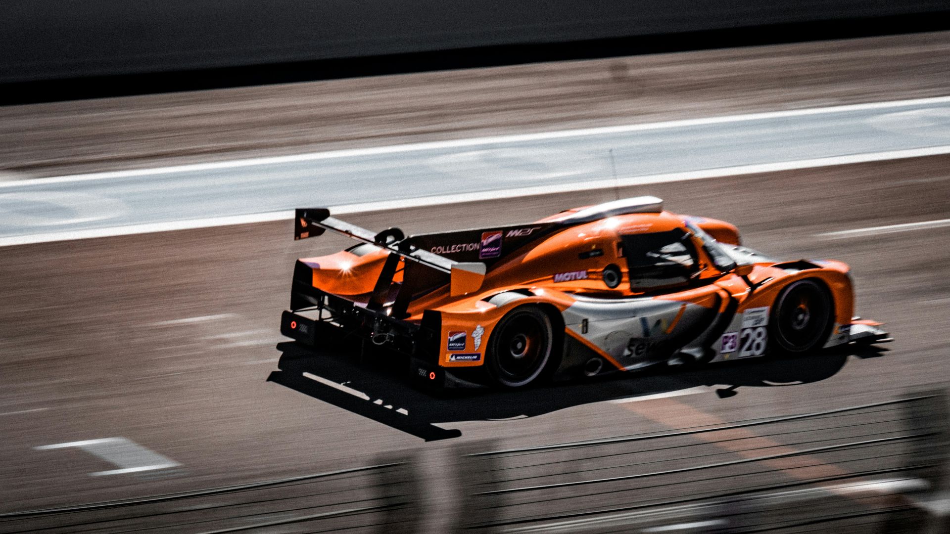 an orange race car driving down a race track