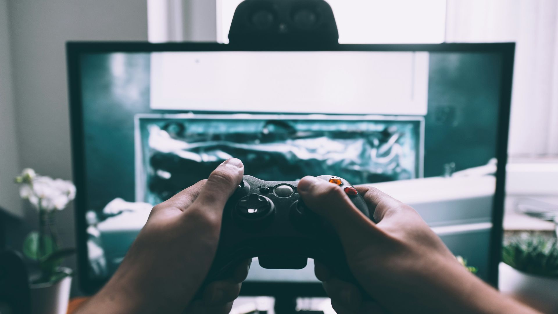 person holding game controller in-front of television