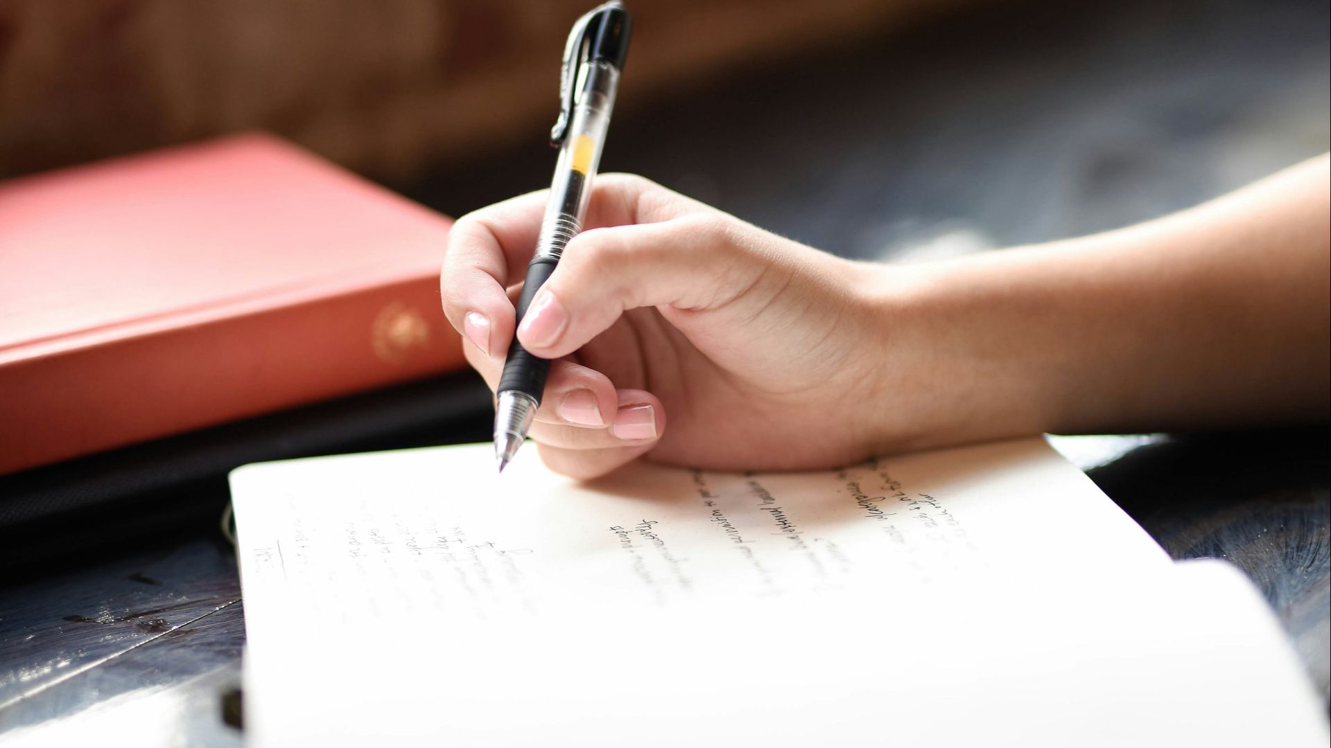 a person writing on a piece of paper with a pen