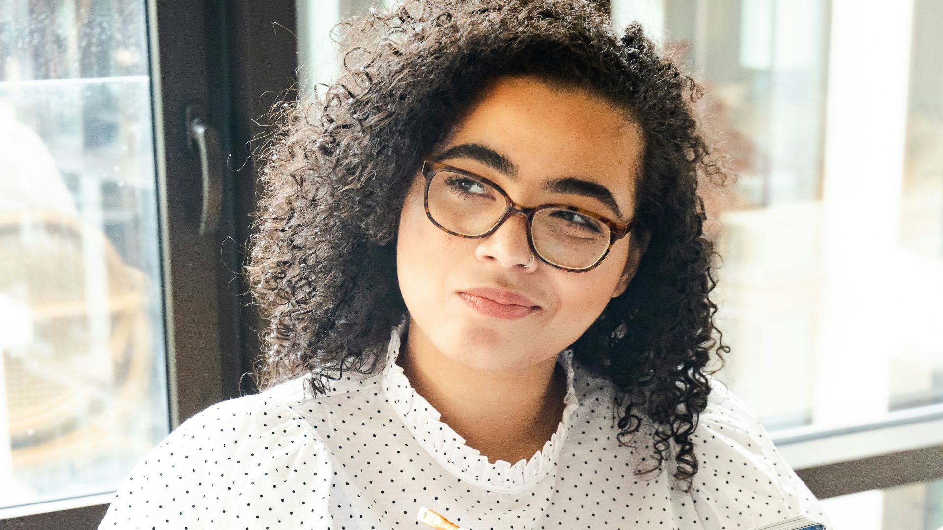 woman in white and black polka dot shirt holding blue and white book