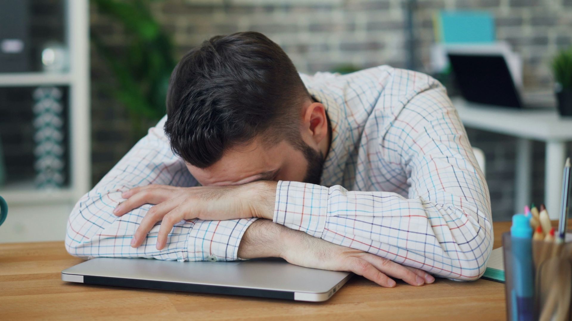 a man sitting at a desk with his head in his hands
