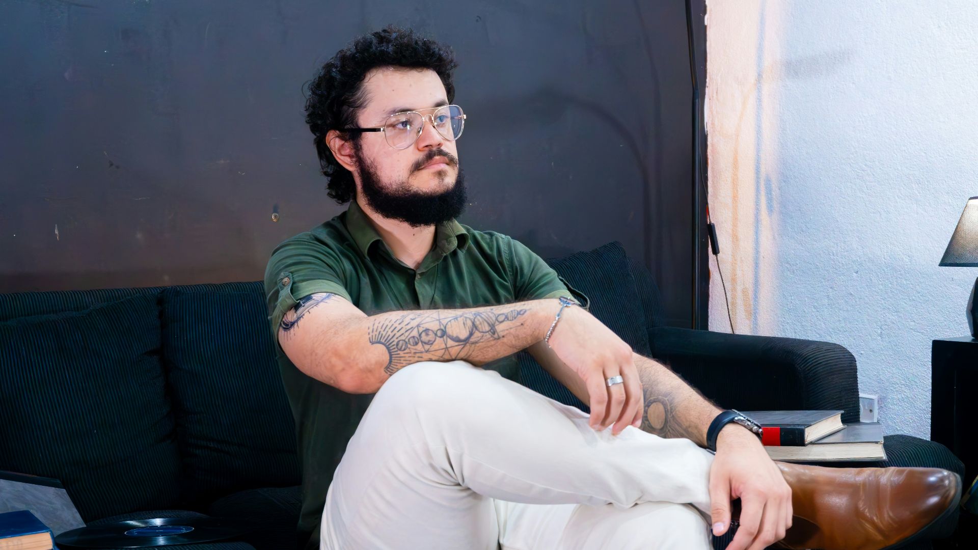 Man with beard and glasses sitting on couch.
