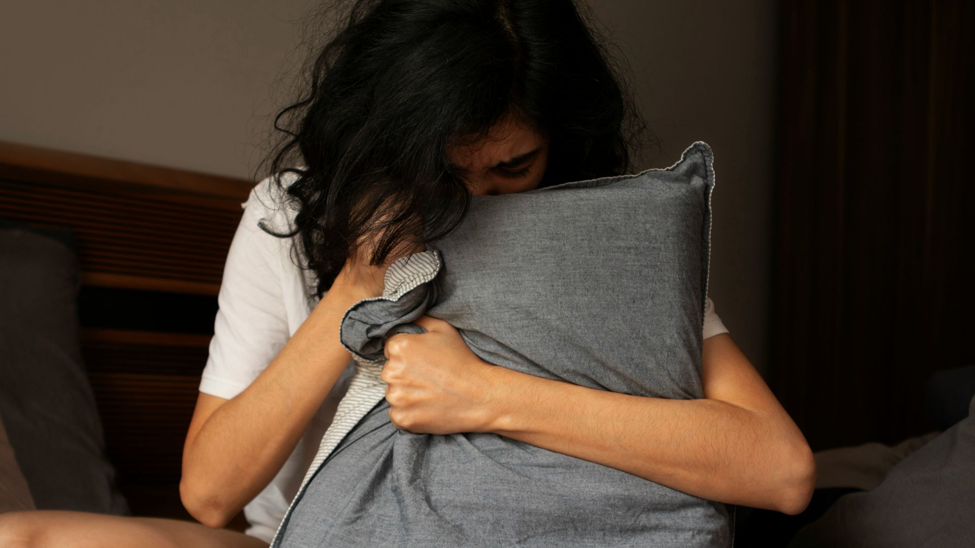A woman sitting on a bed holding a pillow