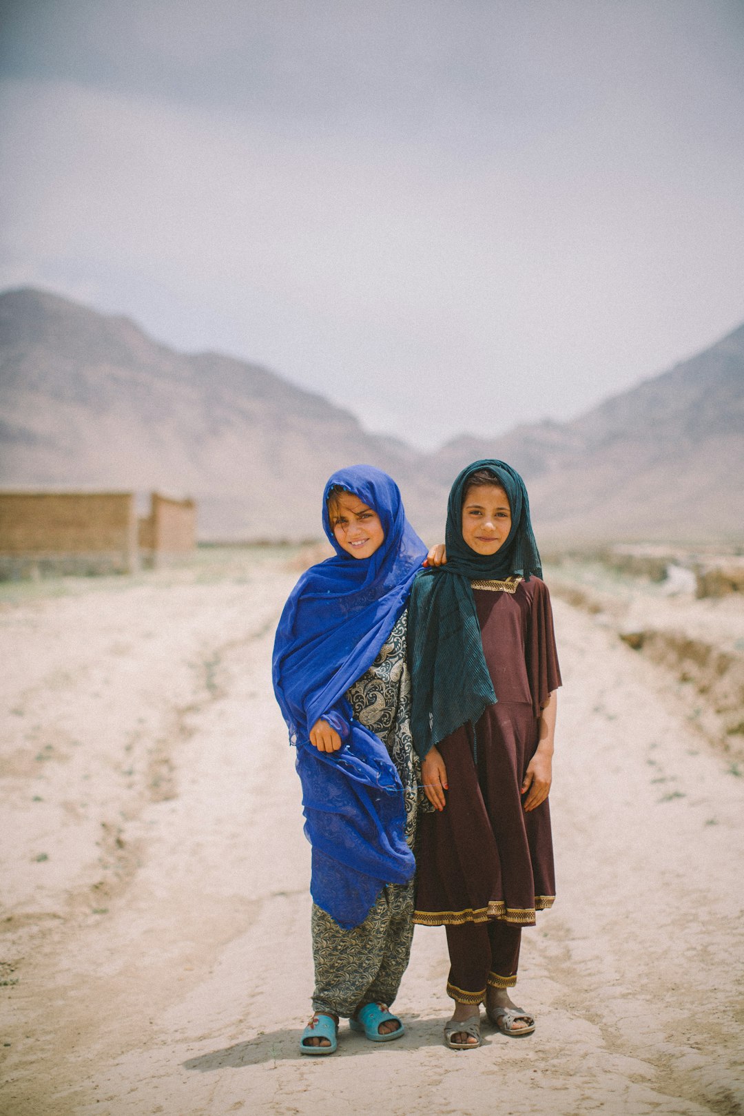 Two women standing in the middle of a dirt road