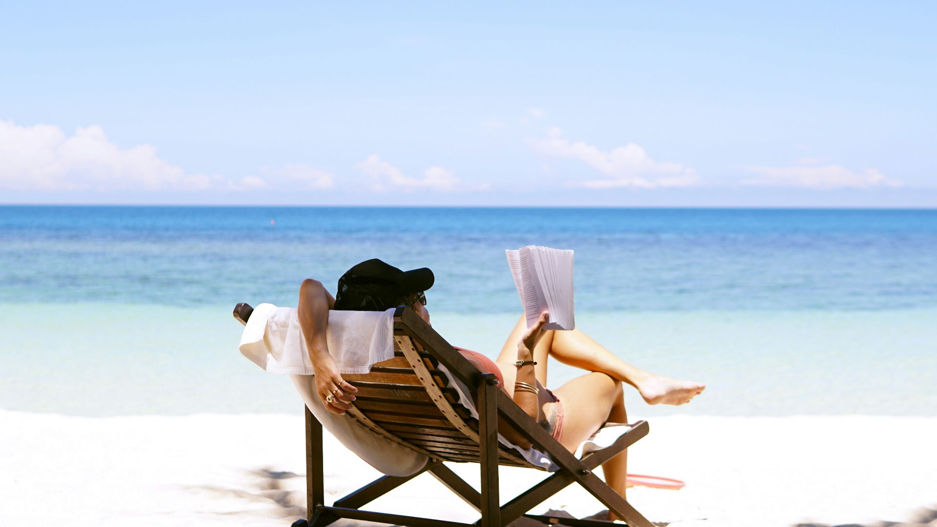 woman sits on brown wooden beach chair