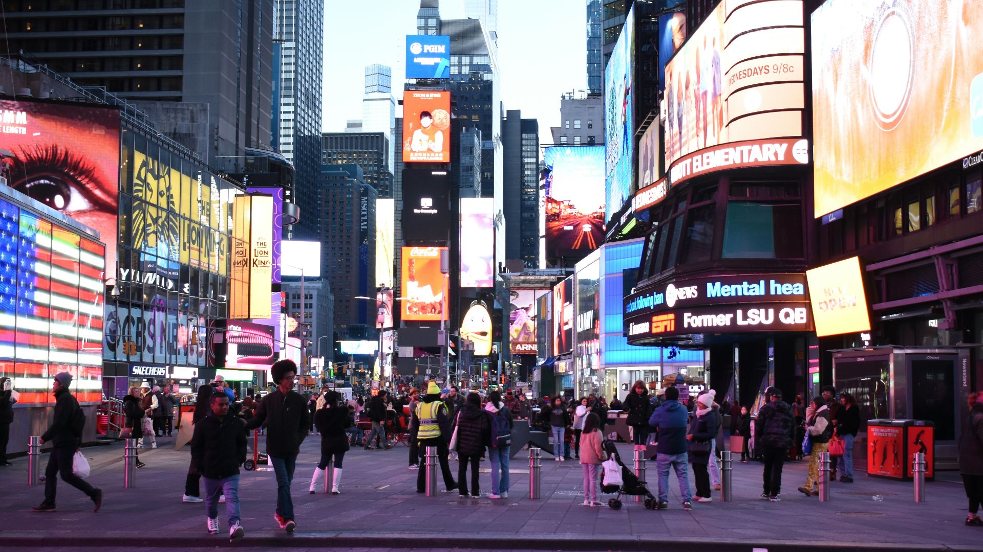 a crowd of people walking down a street next to tall buildings