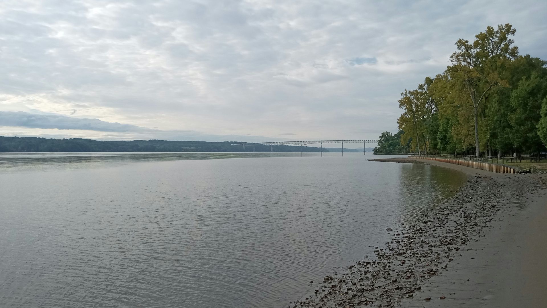 A body of water surrounded by trees and clouds