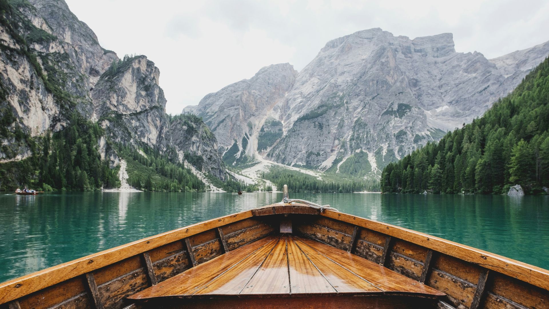 brown wooden boat moving towards the mountain