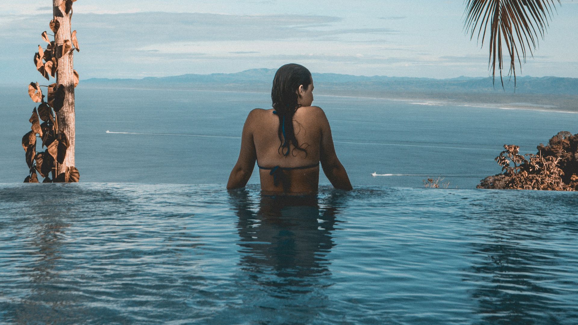 woman wearing black bikini tap swimming on body of water between trees