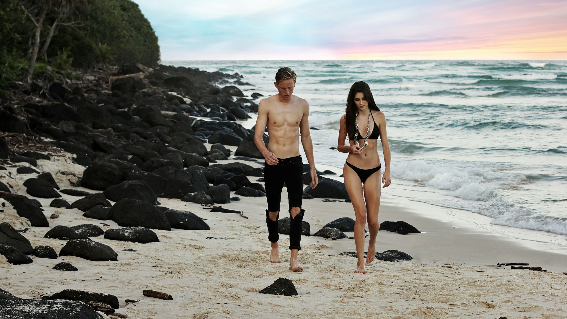 man and woman walking beside body of water