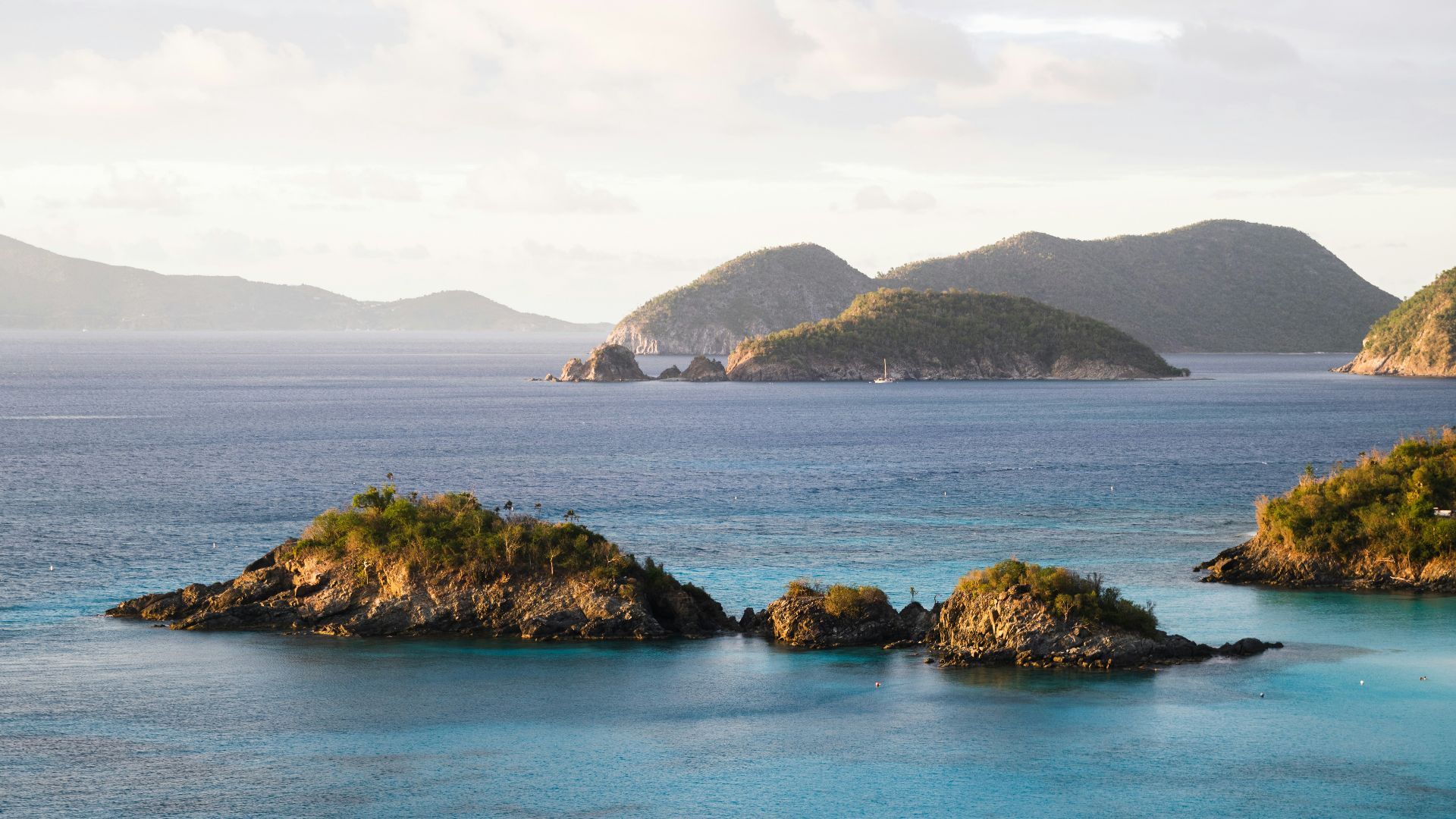 brown and green island on blue sea under white clouds during daytime