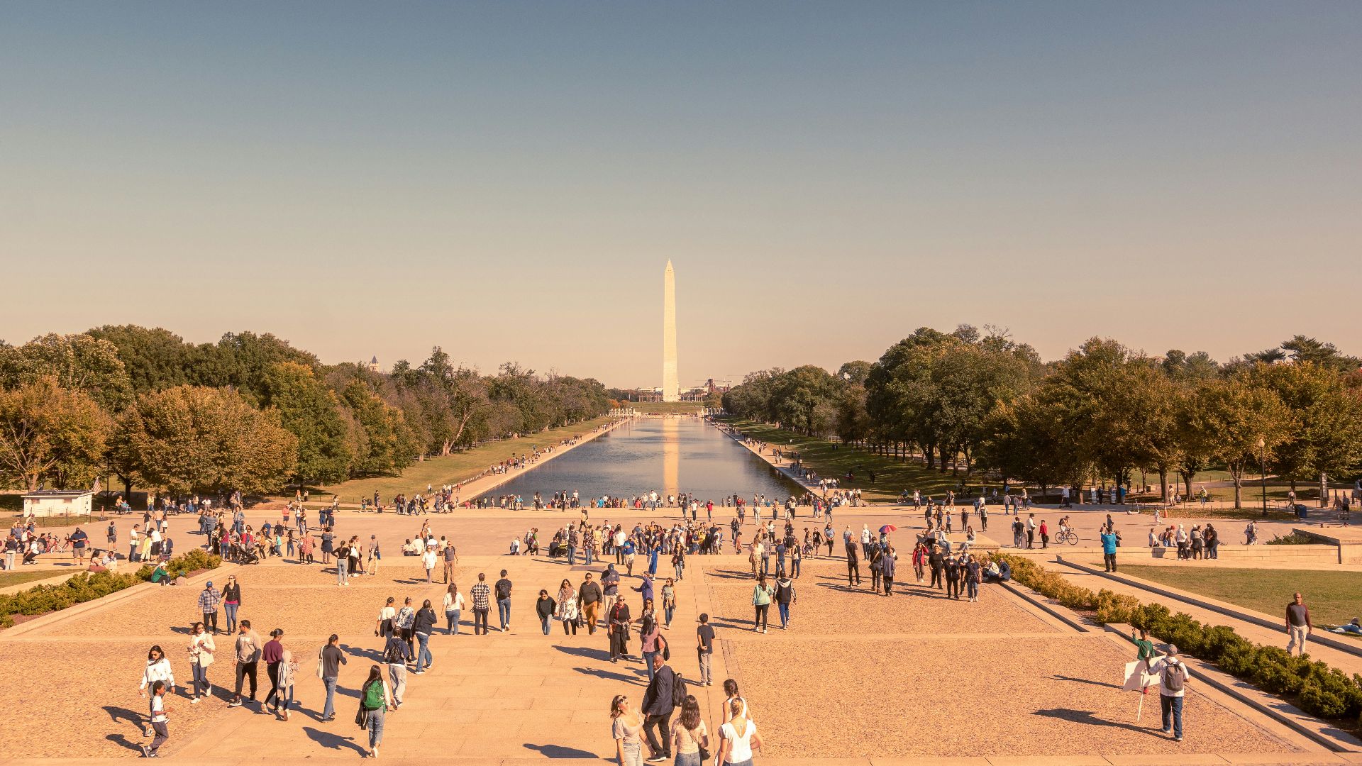 a large group of people walking around a monument with National Mall in the background